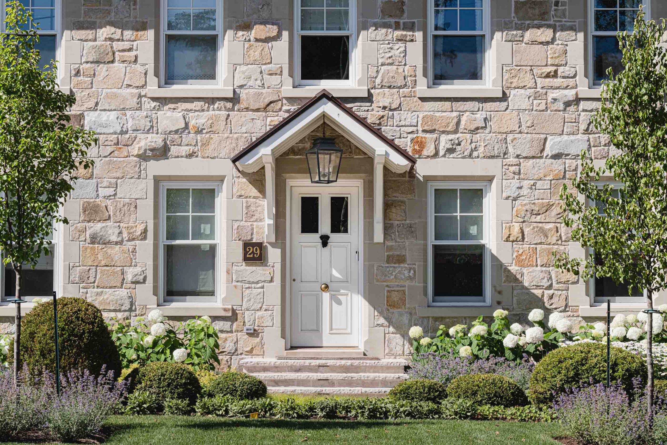 English cottage-style stone house with masonry and copper roof detail