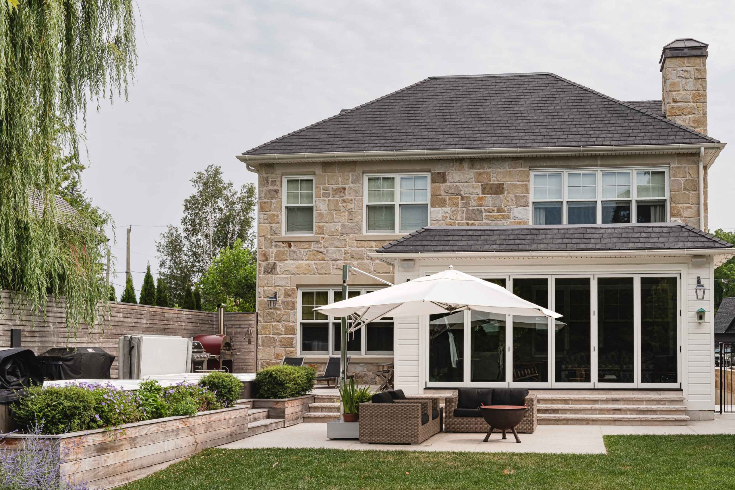 Backyard of an English-style stone house with contemporary pool and lounge area