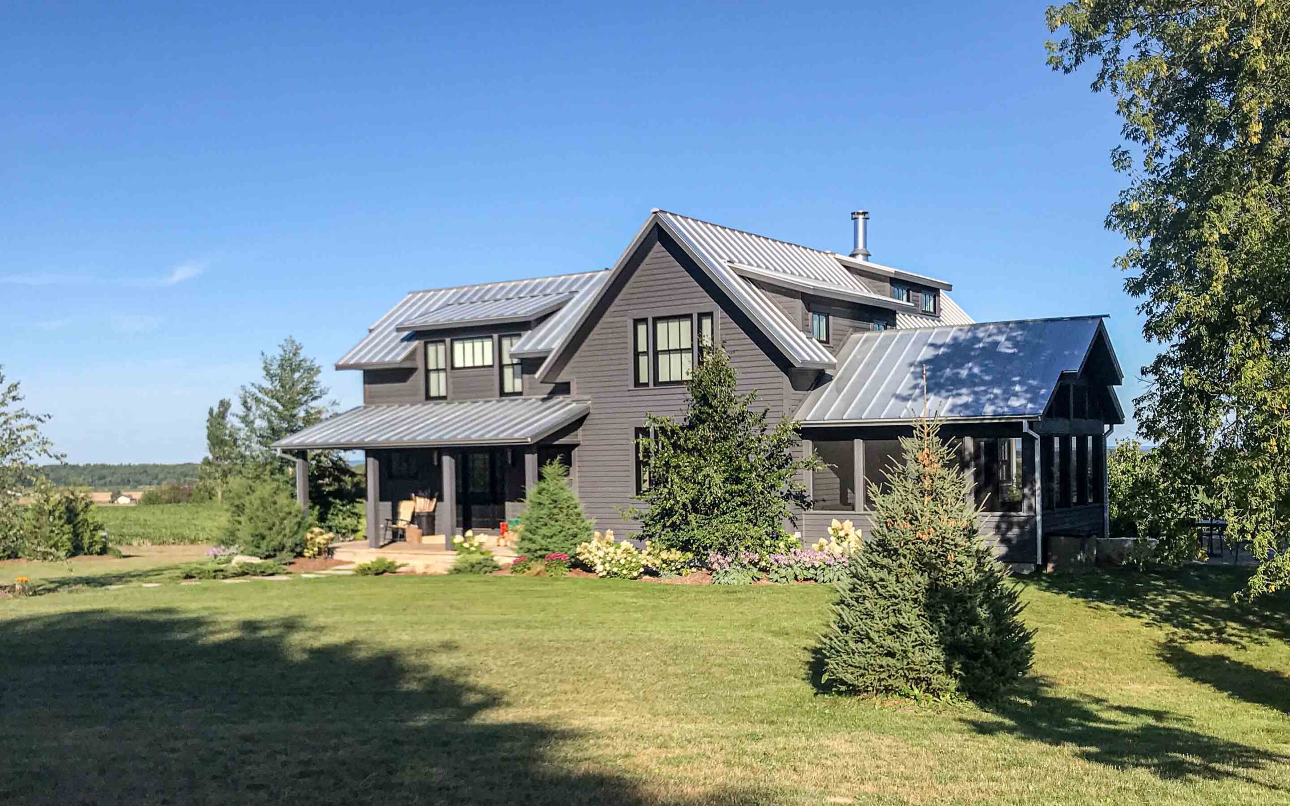 The exterior of a contemporary farmhouse up on a hill. Built by Blake Farrow Project Management, designed by IBI Group Architects