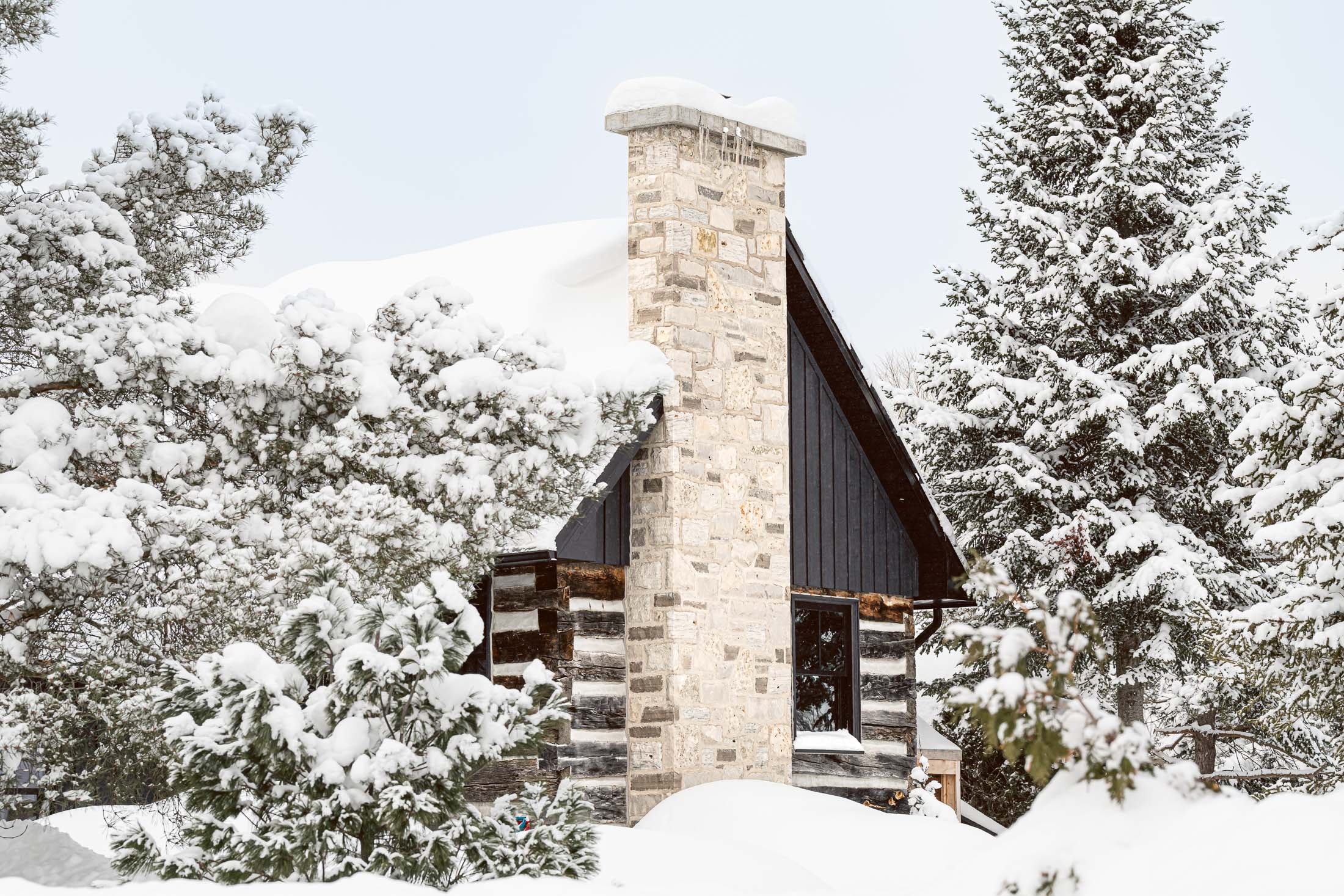 exterior detail of a restored stone chimney on a log cabin renovation