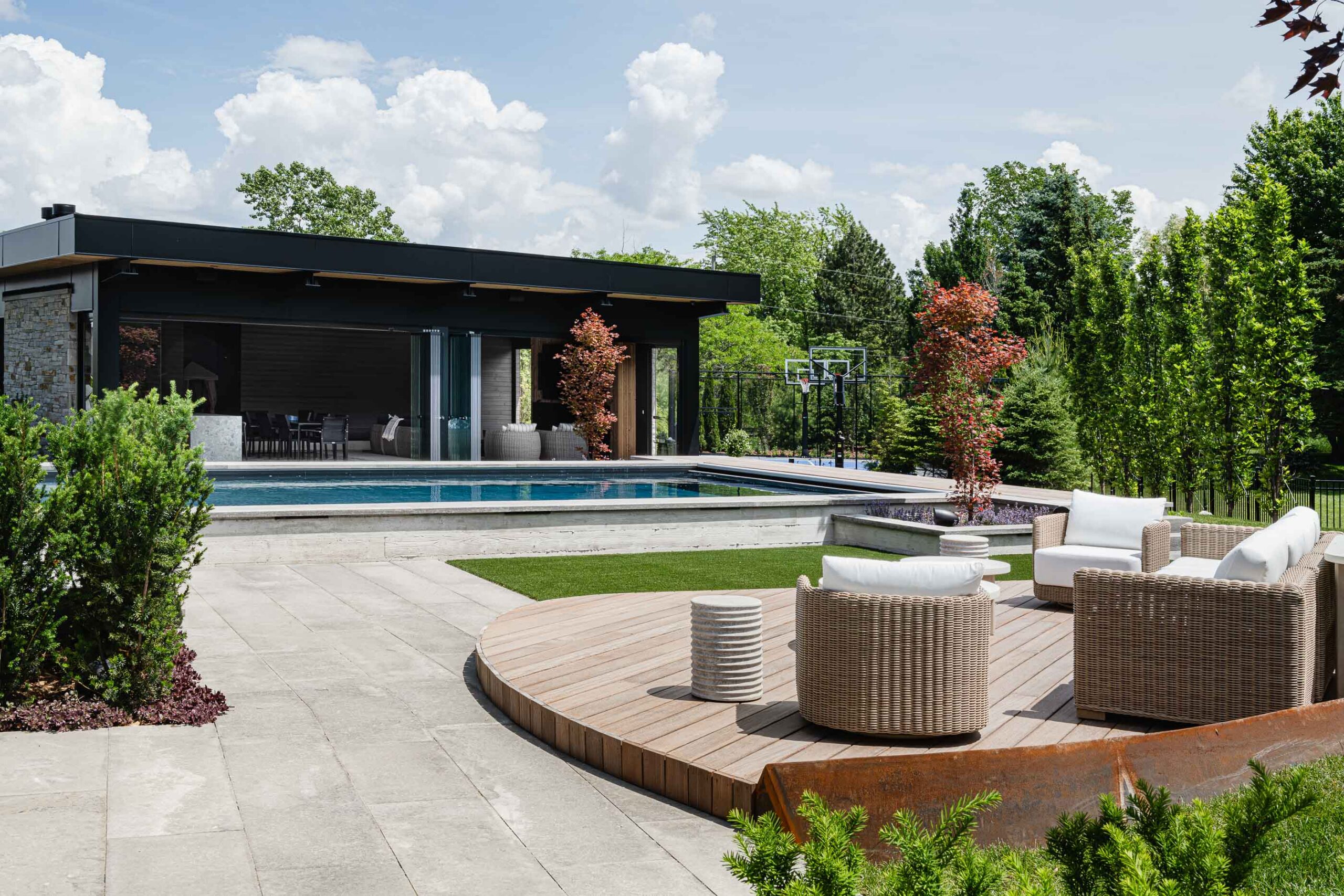 Collingwood custom home builder project featuring luxury backyard with custom. elevated wood seating areas, pool, and pool house with retractable glass walls