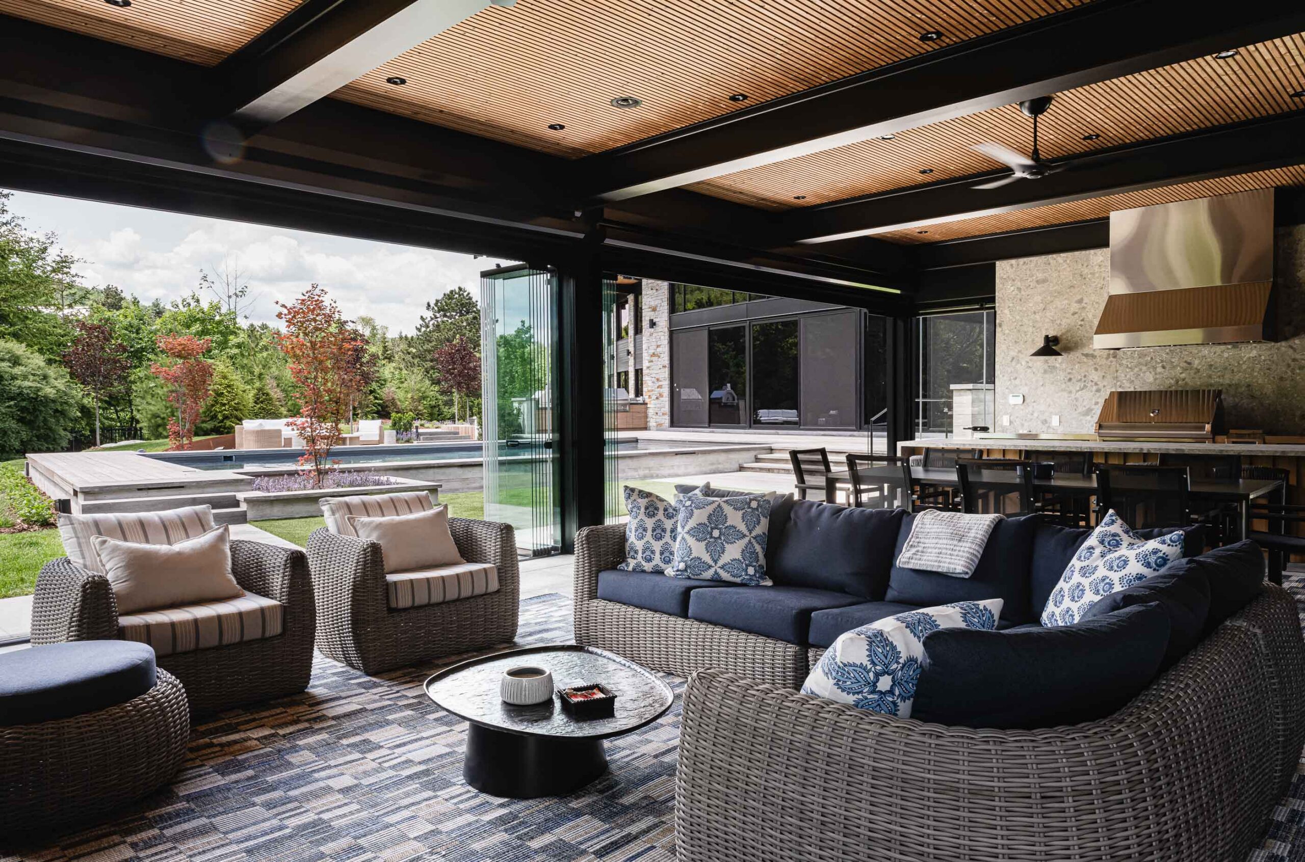 Luxury Blue Mountain custom pool house with open retractable glass walls connecting indoor living and dining spaces to the pool and outdoor entertaining area