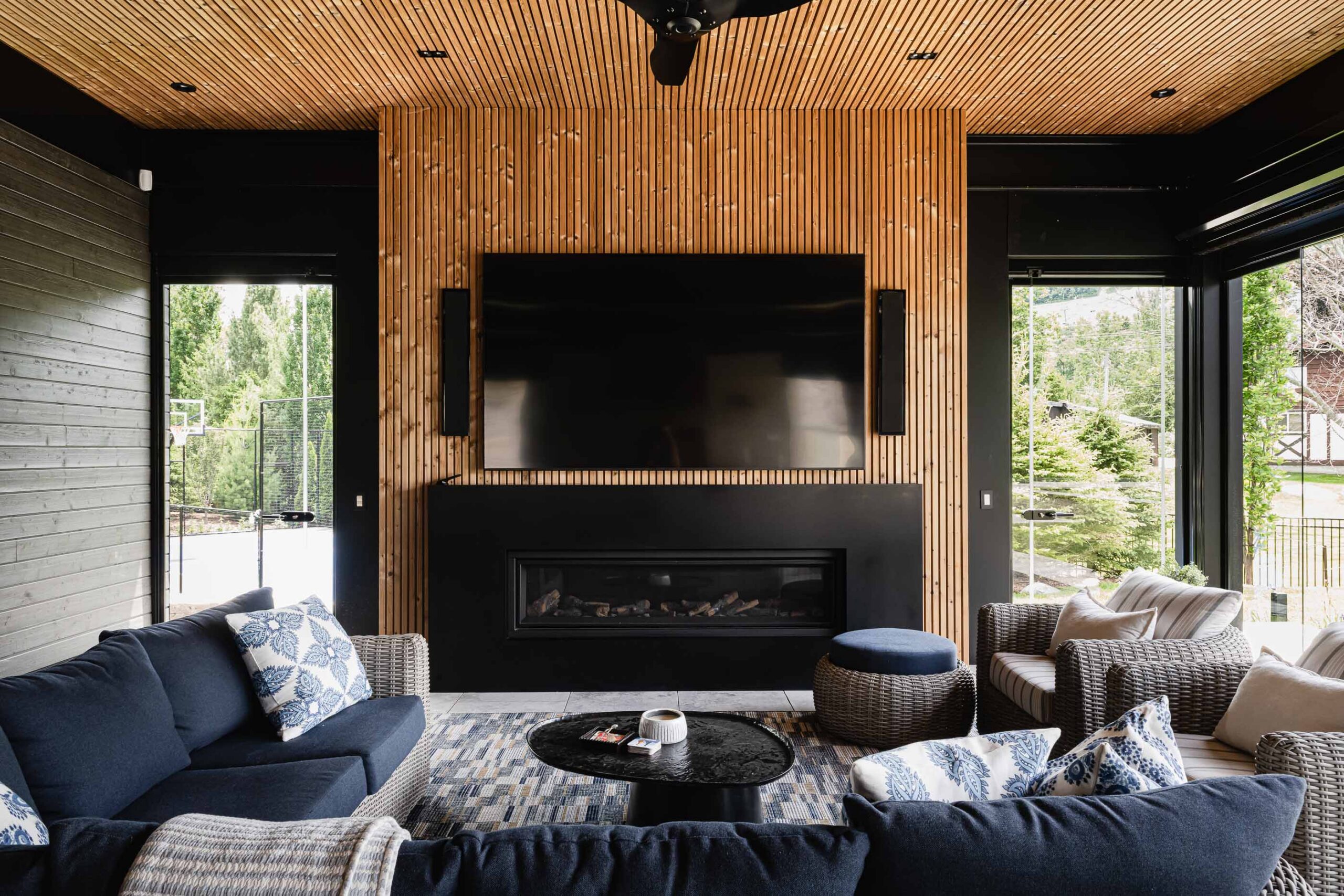 Luxury Collingwood pool house with slat wood detailing, and seating area with fireplace and TV for watching the game