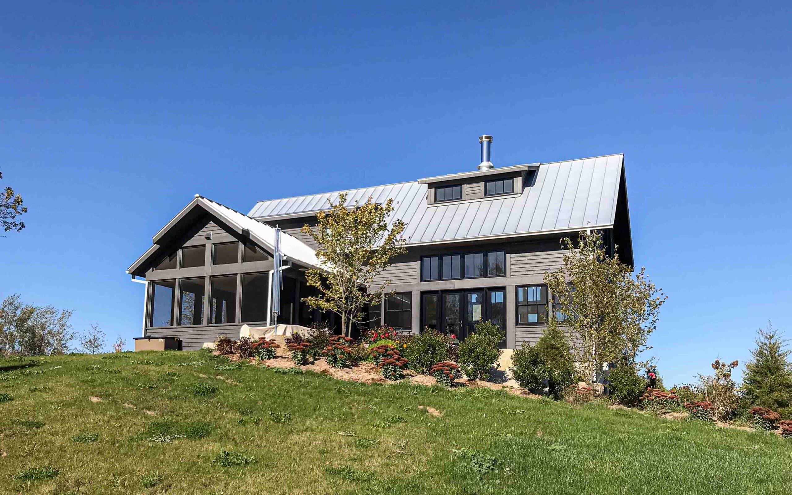 The exterior of a contemporary farmhouse up on a hill. Built by Blake Farrow Project Management, designed by IBI Group Architects