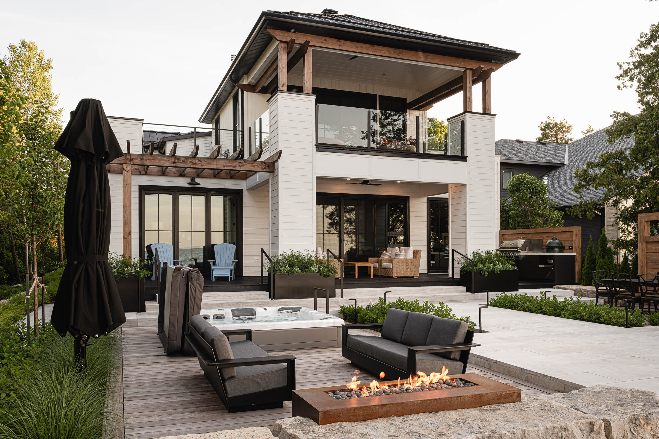 Spacious outdoor living area with hot tub and individual seating areas by Collingwood custom home builder