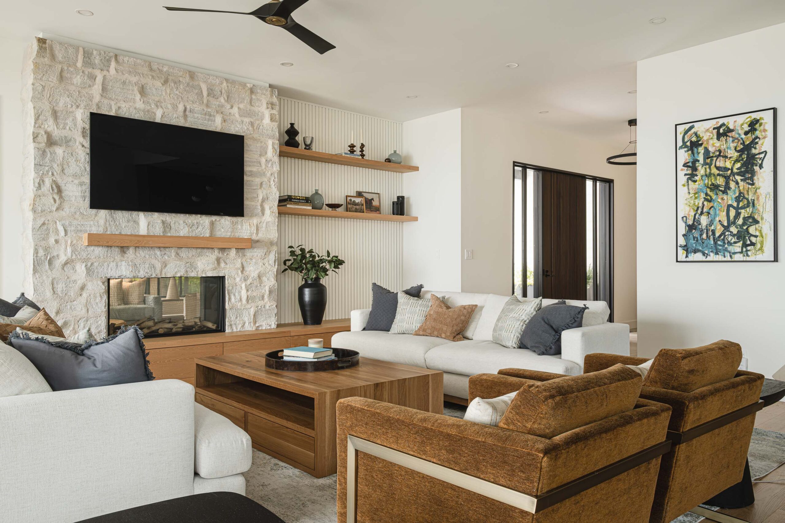 Natural stone fireplace, custom oak cabinetry, and shiplap detailing in a waterfront modern beach house