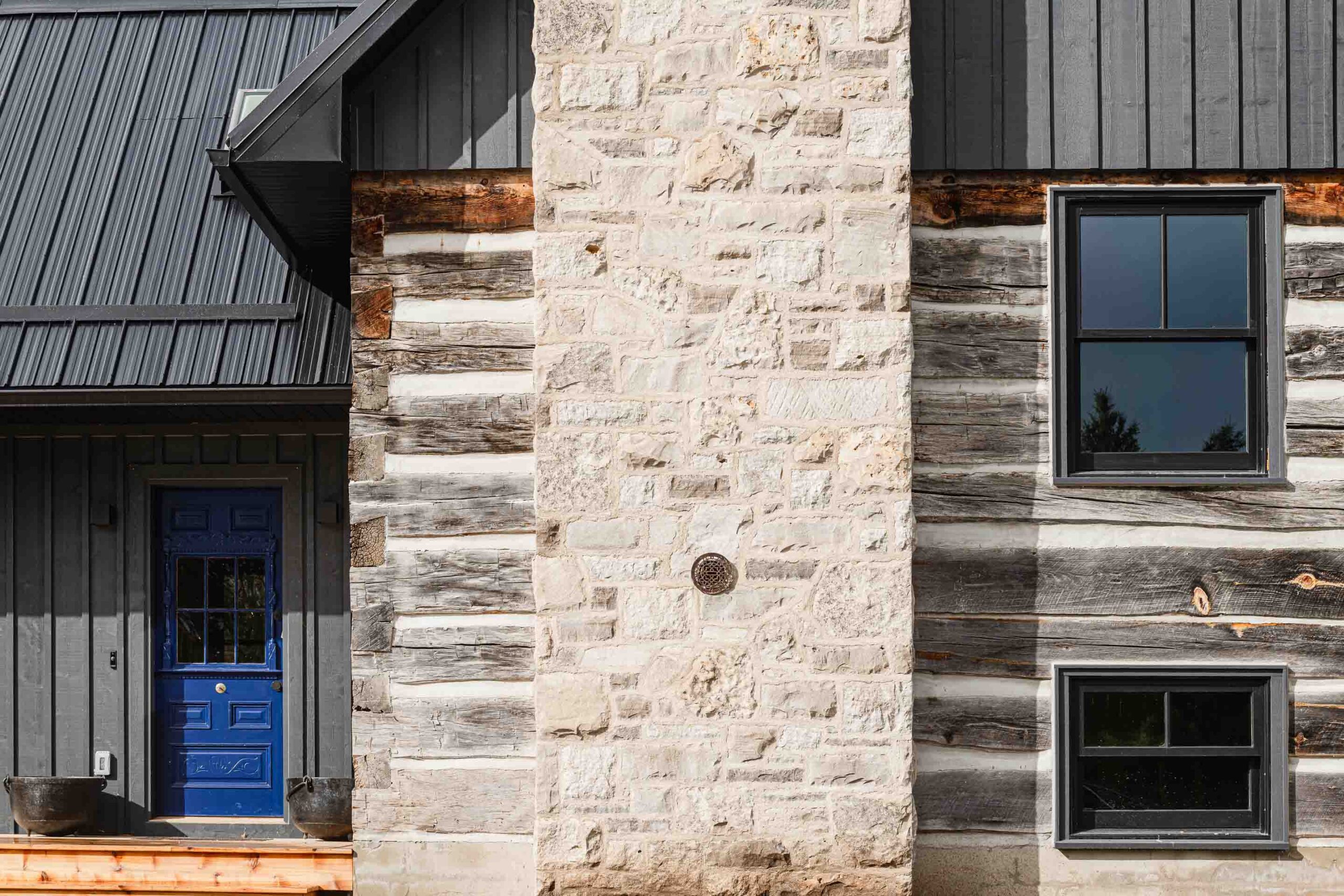 exterior detail of the stone chimney and log exterior of a modernized rustic chalet renovation by Blake Farrow Project