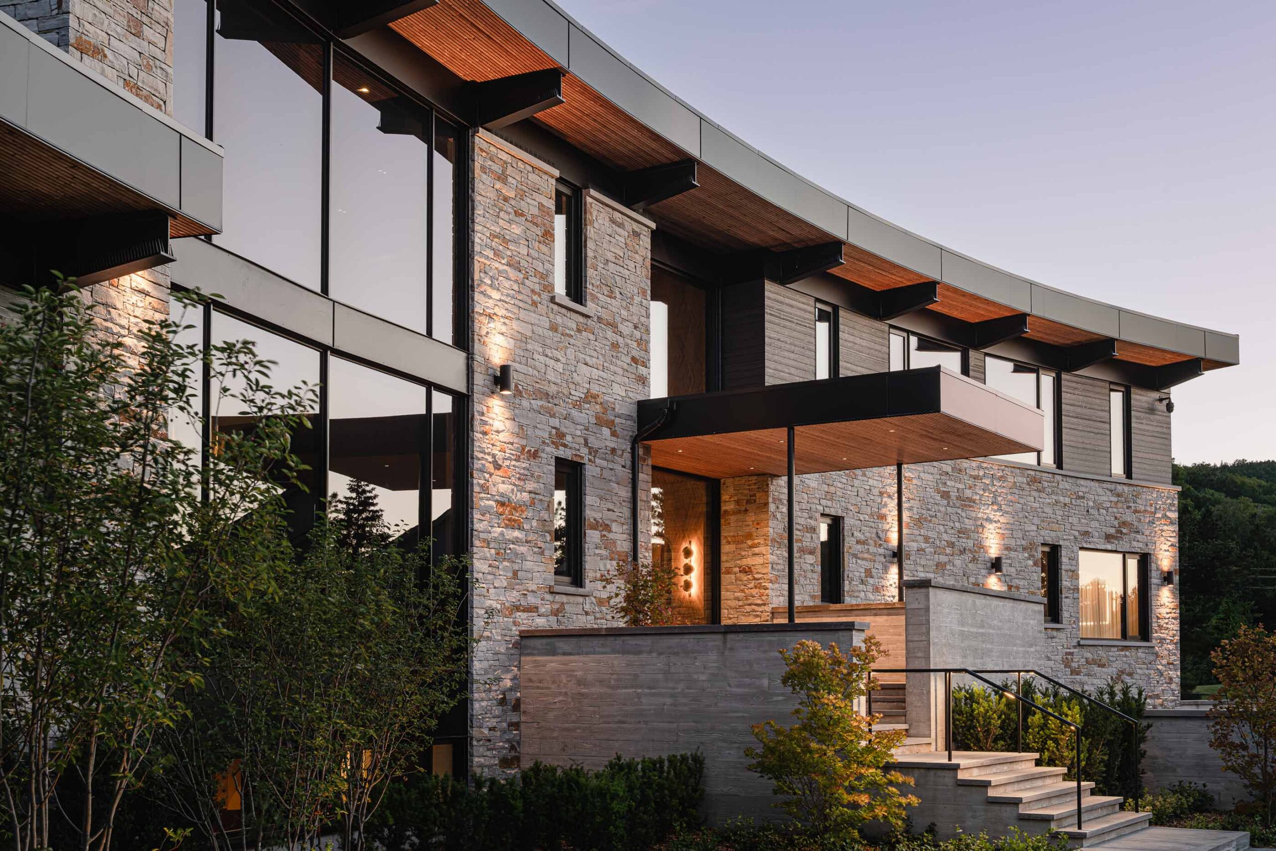 Curved stone wall detail with evening lighting, on a luxury custom chalet built by a Collingwood custom home builder