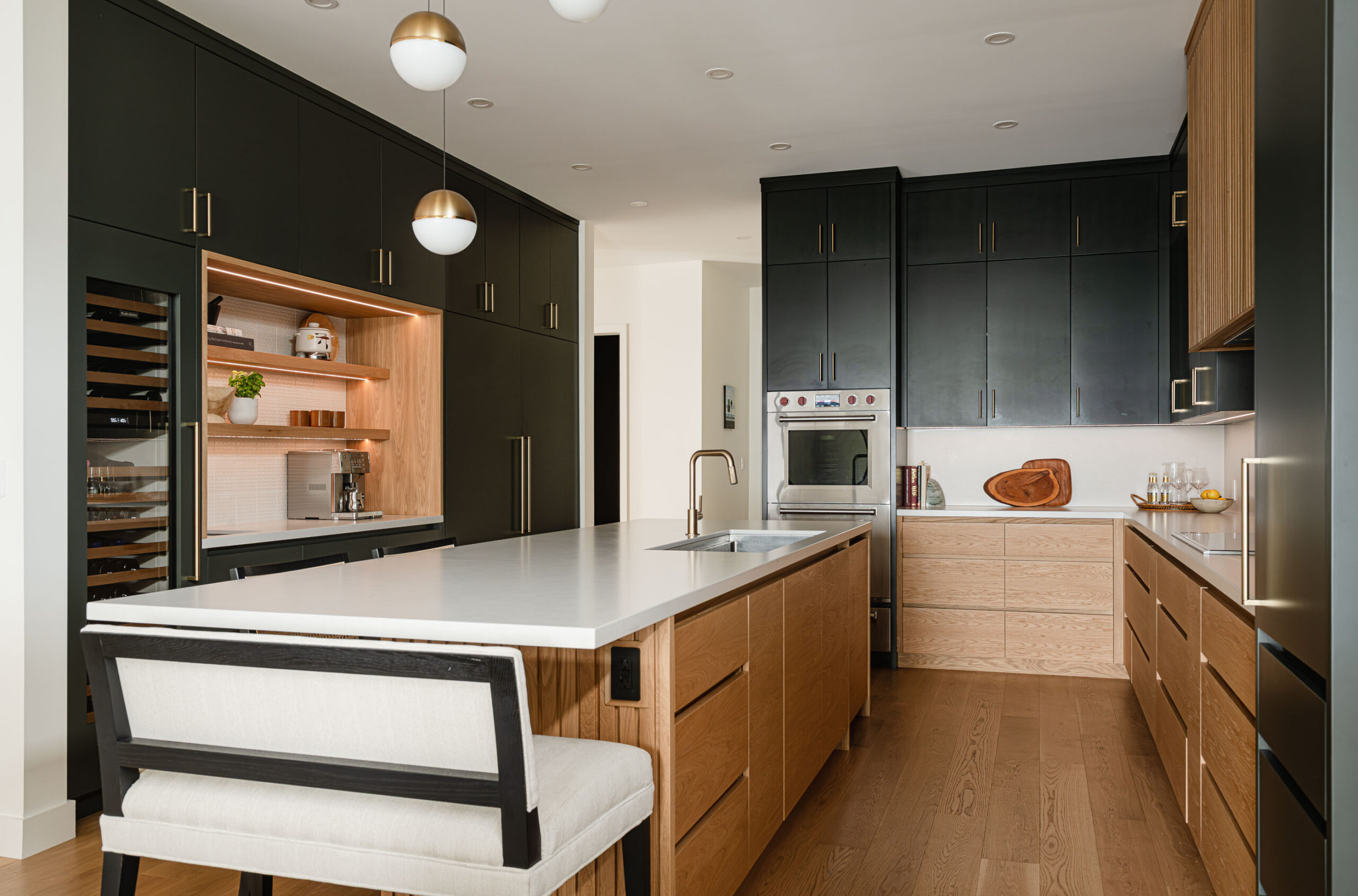 Contemporary kitchen with fluted wood detailing, charcoal custom cabinetry, quartz counters, and a custom beverage station