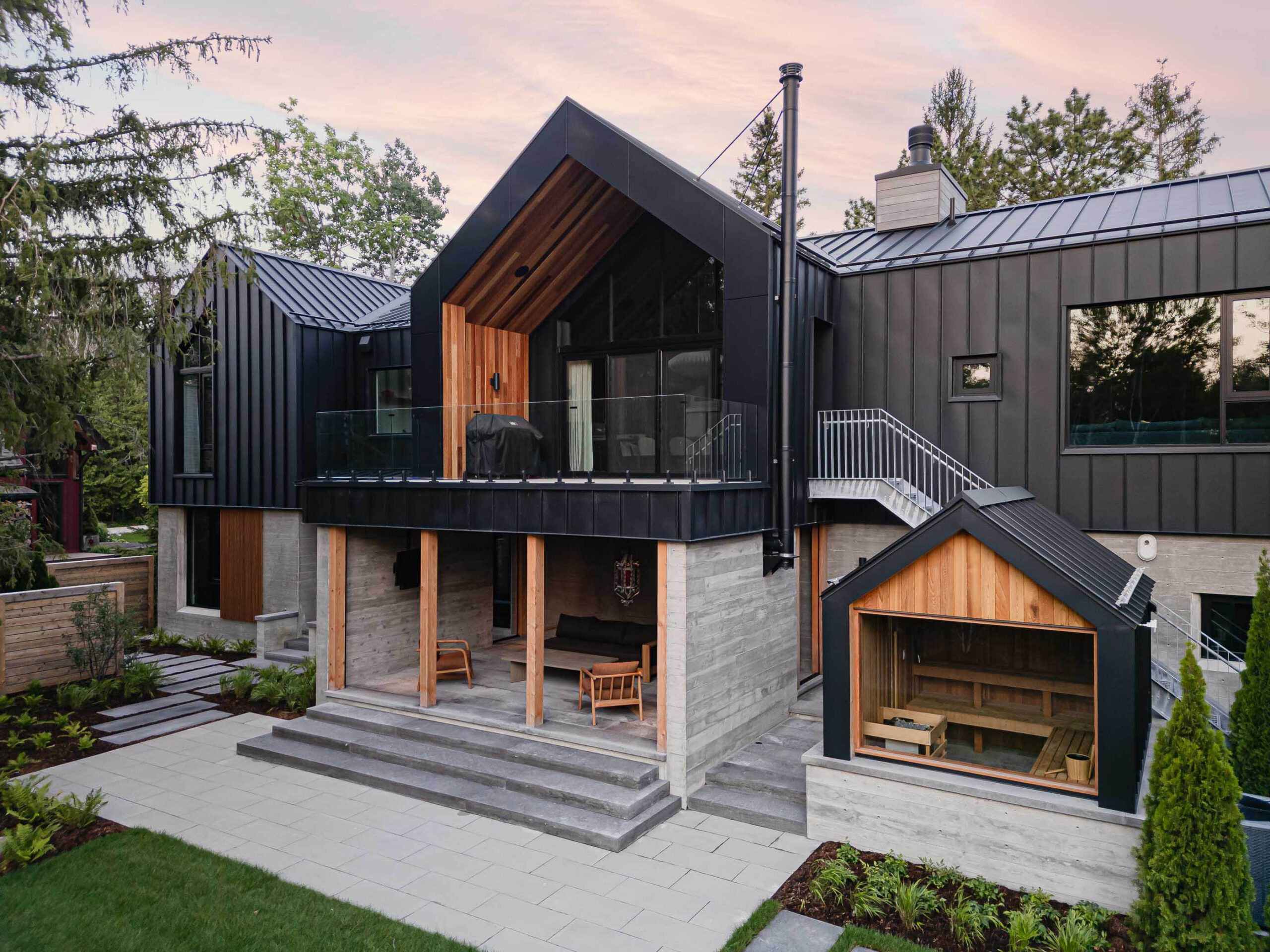 Contemporary Blue Mountain chalet rear elevation featuring board-formed concrete walls, black metal siding and attached sauna