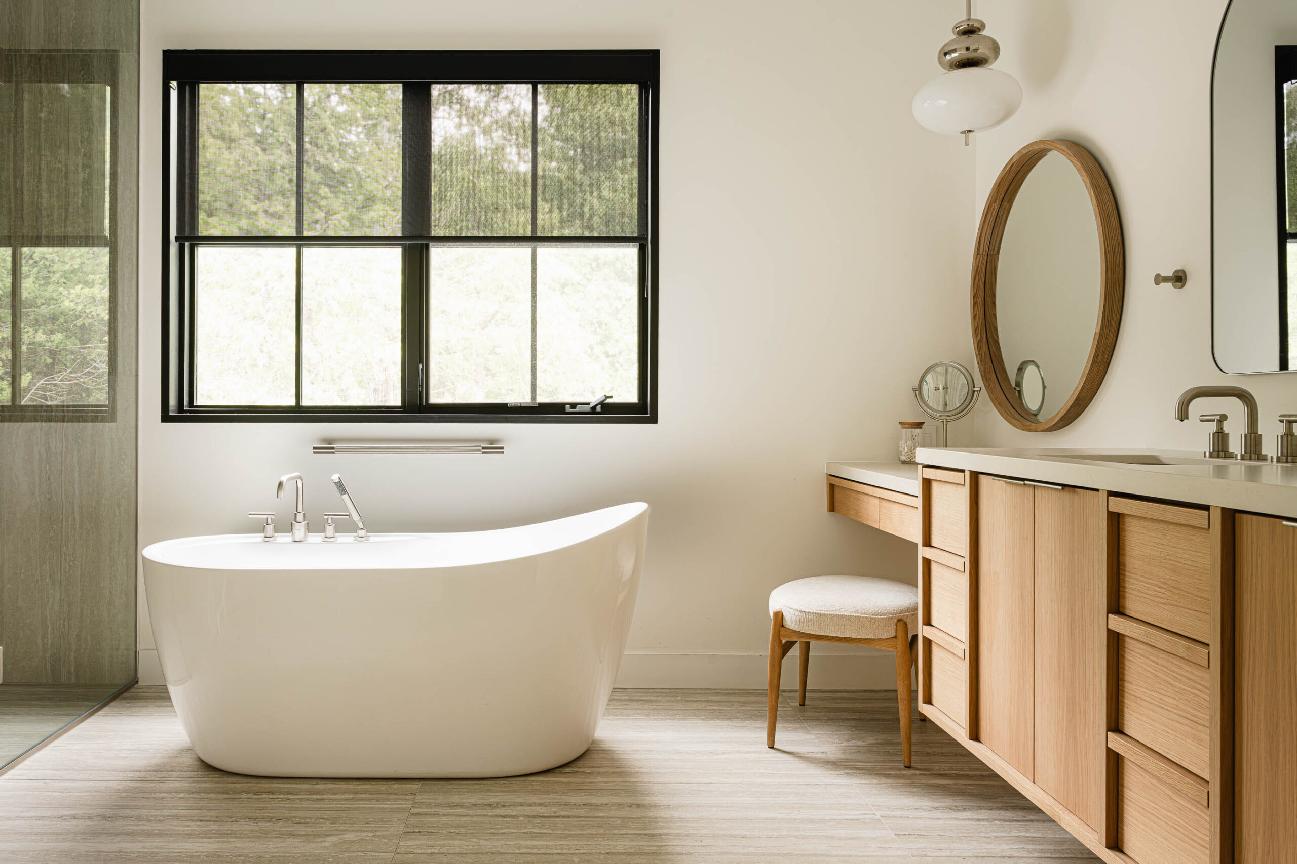 Custom floating vanity, quartz counters and modern standing tub in the primary bathroom of a custom beach house built by a Collingwood custom home builder