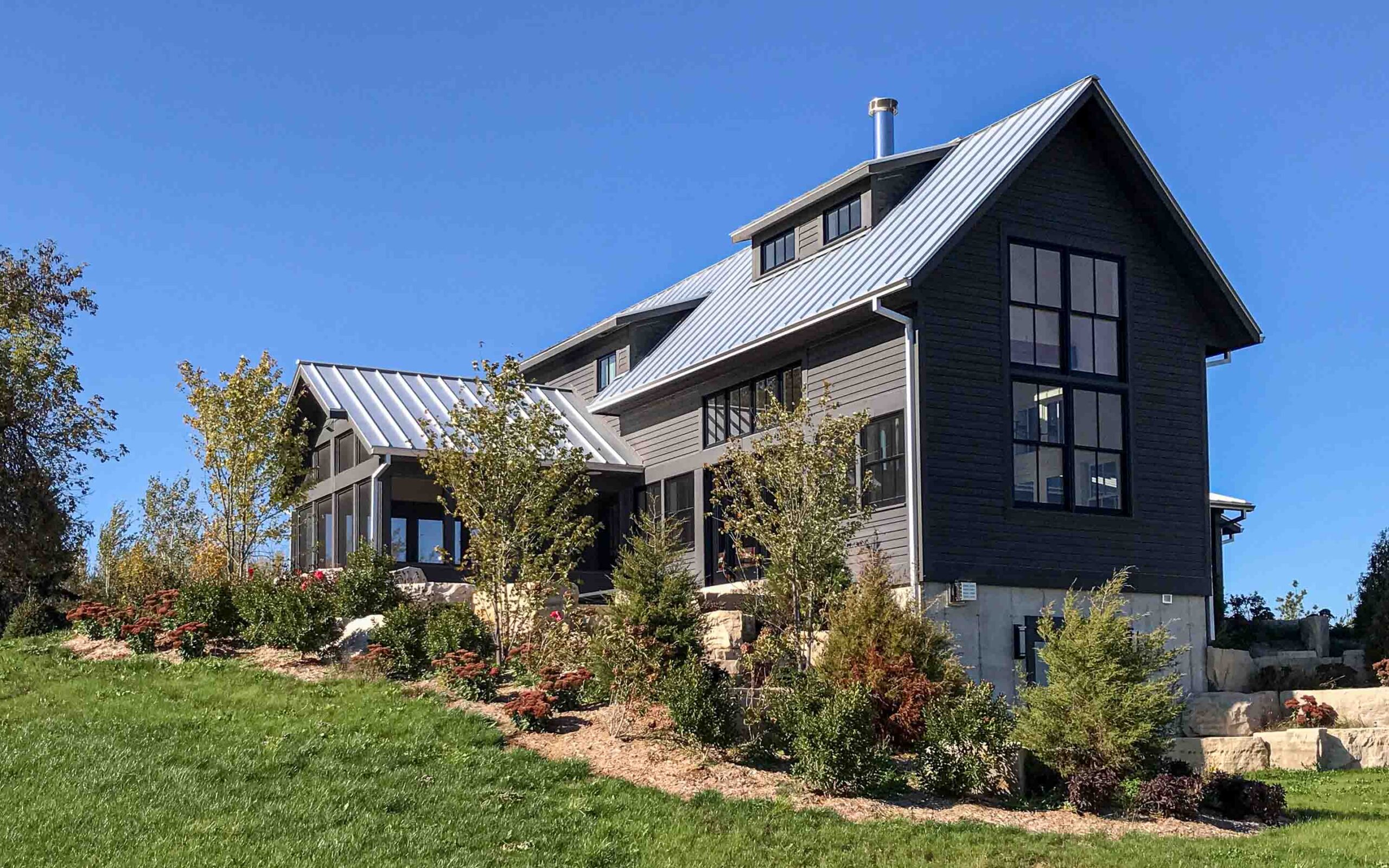 The exterior of a contemporary farmhouse up on a hill. Built by Blake Farrow Project Management, designed by IBI Group Architects