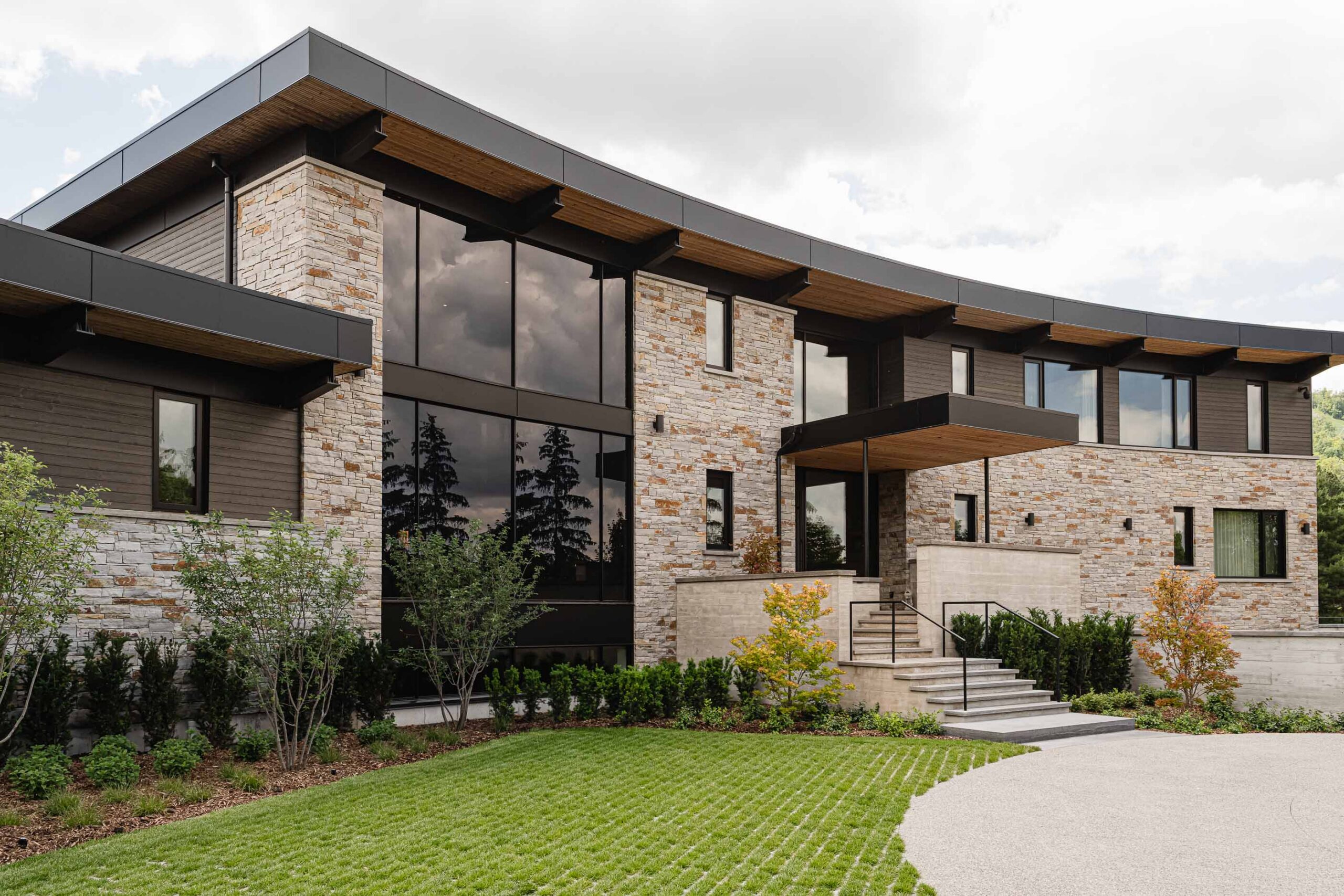 Front elevation of a stone-clad luxury chalet with distinctive curved architecture built by a Collingwood custom home builder
