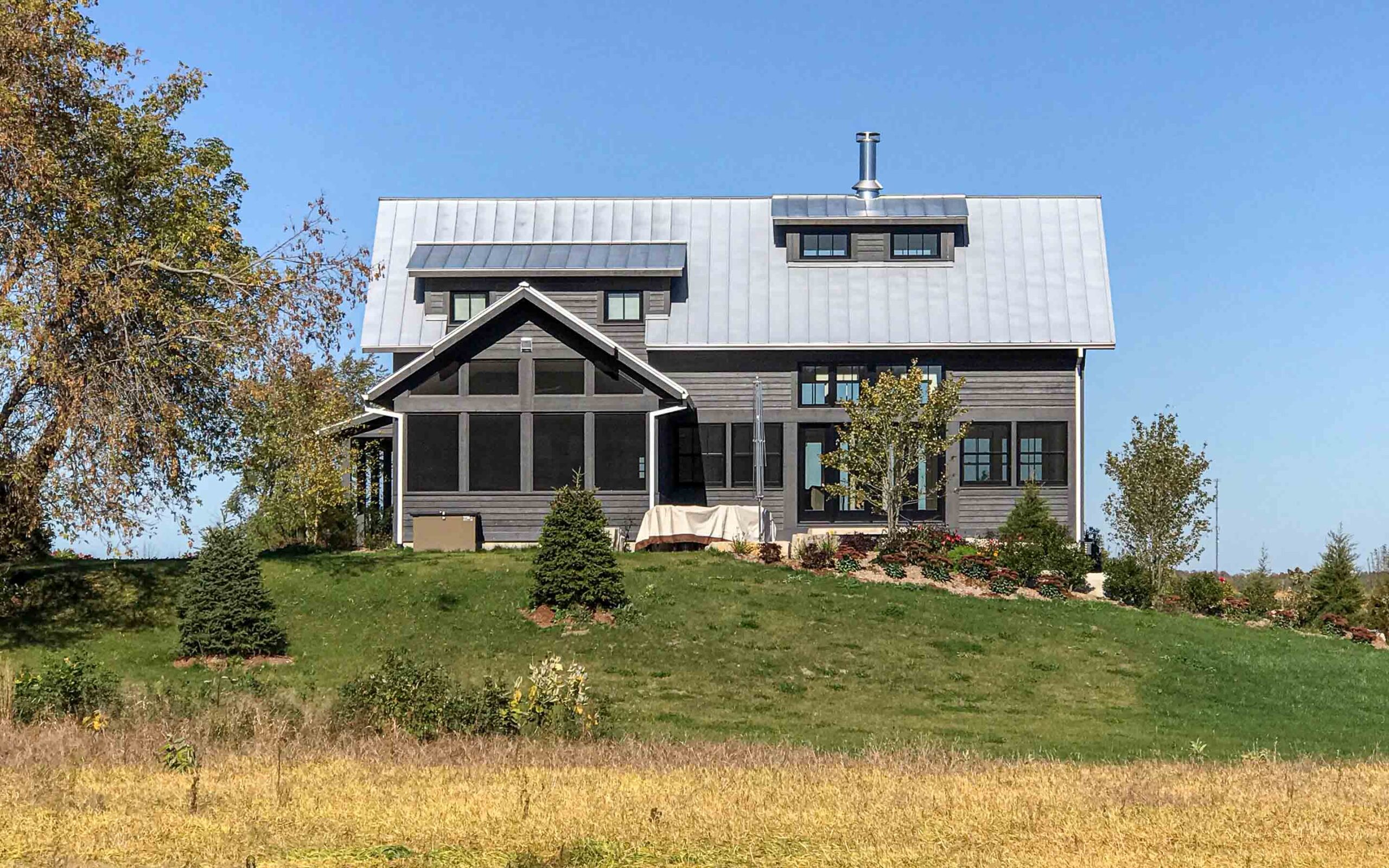 The exterior of a contemporary farmhouse up on a hill. Built by Blake Farrow Project Management, designed by IBI Group Architects