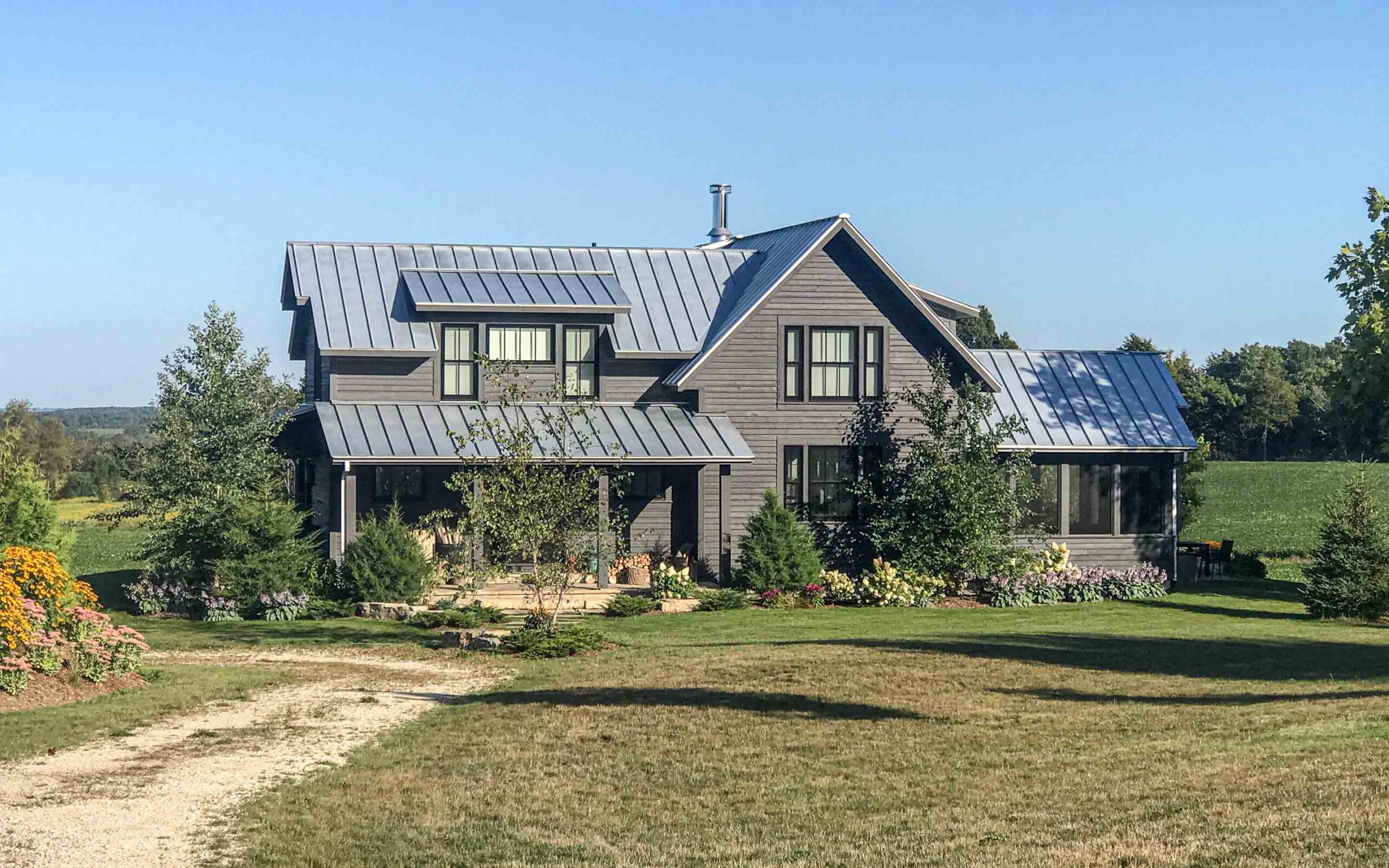 The exterior of a contemporary farmhouse up on a hill. Built by Blake Farrow Project Management, designed by IBI Group Architects