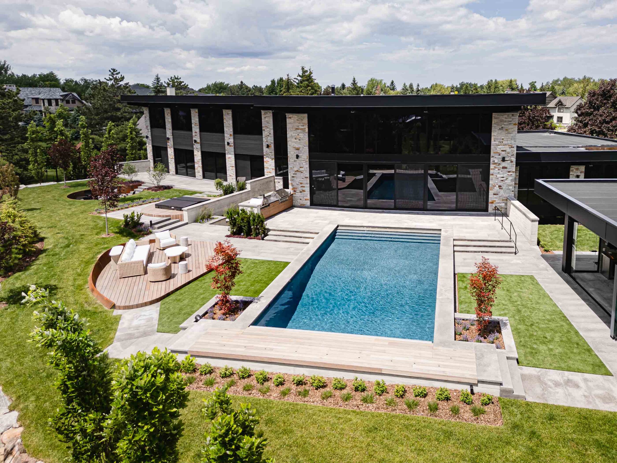 Aerial backyard view of a custom Blue Mountain luxury home with pool, pool house, expansive landscaping and numerous seating areas