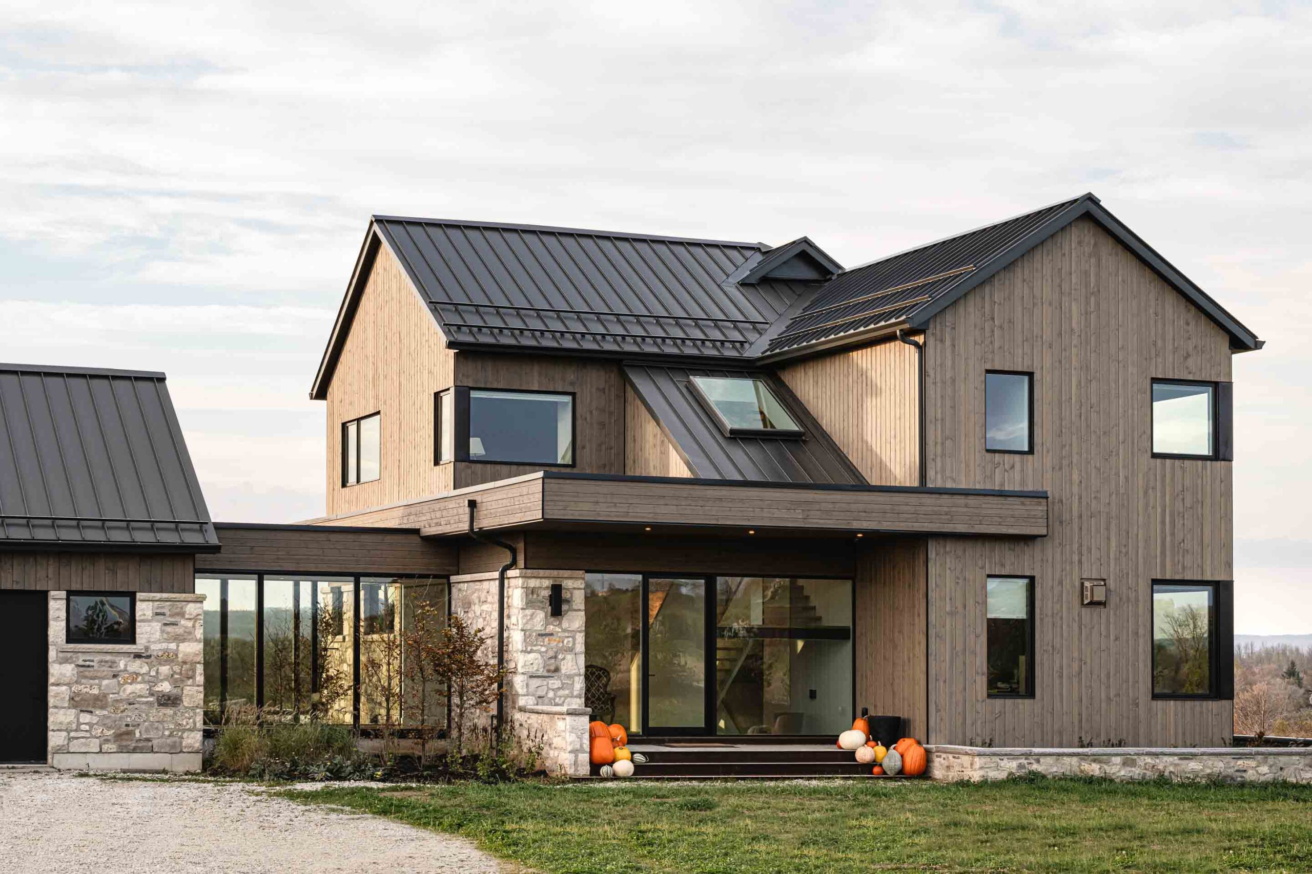 Front architectural detail showcasing the modern lines of a contemporary farmhouse crafted with stone, metal, wood and glass