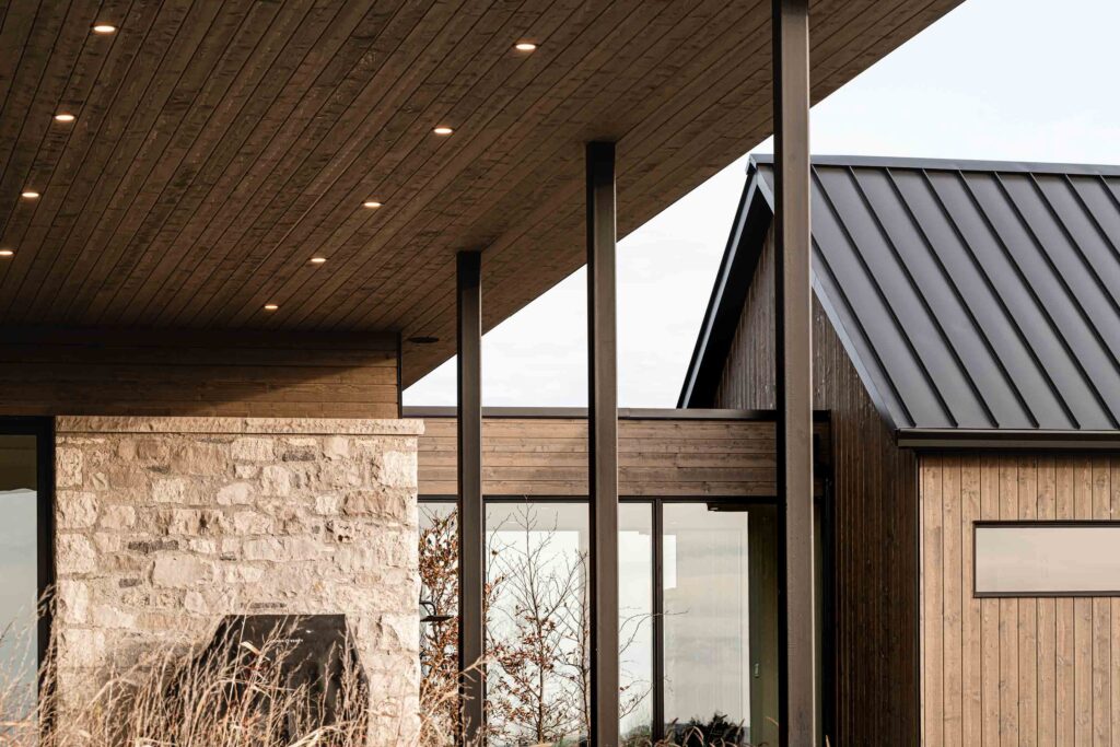 Architectural detail of a contemporary farmhouse, featuring stone, wood and metal materials and modern lines