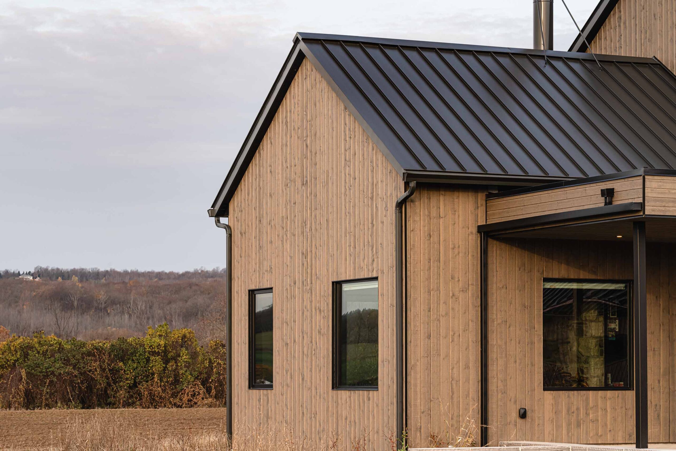 Warm light hits the exterior of a contemporary farmhouse with rich, wood siding and modern lines