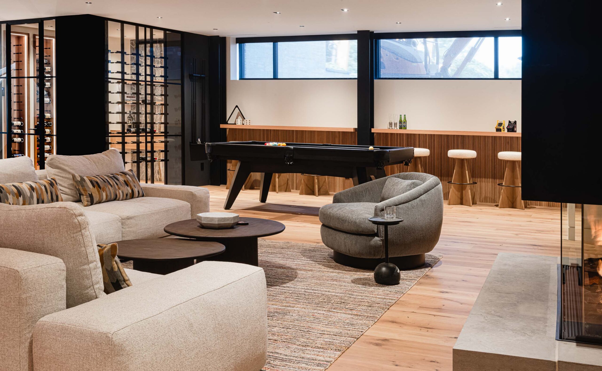 Contemporary rec room in a Blue Mountain chalet with fireplace seating area, pool table and glass wine cellar