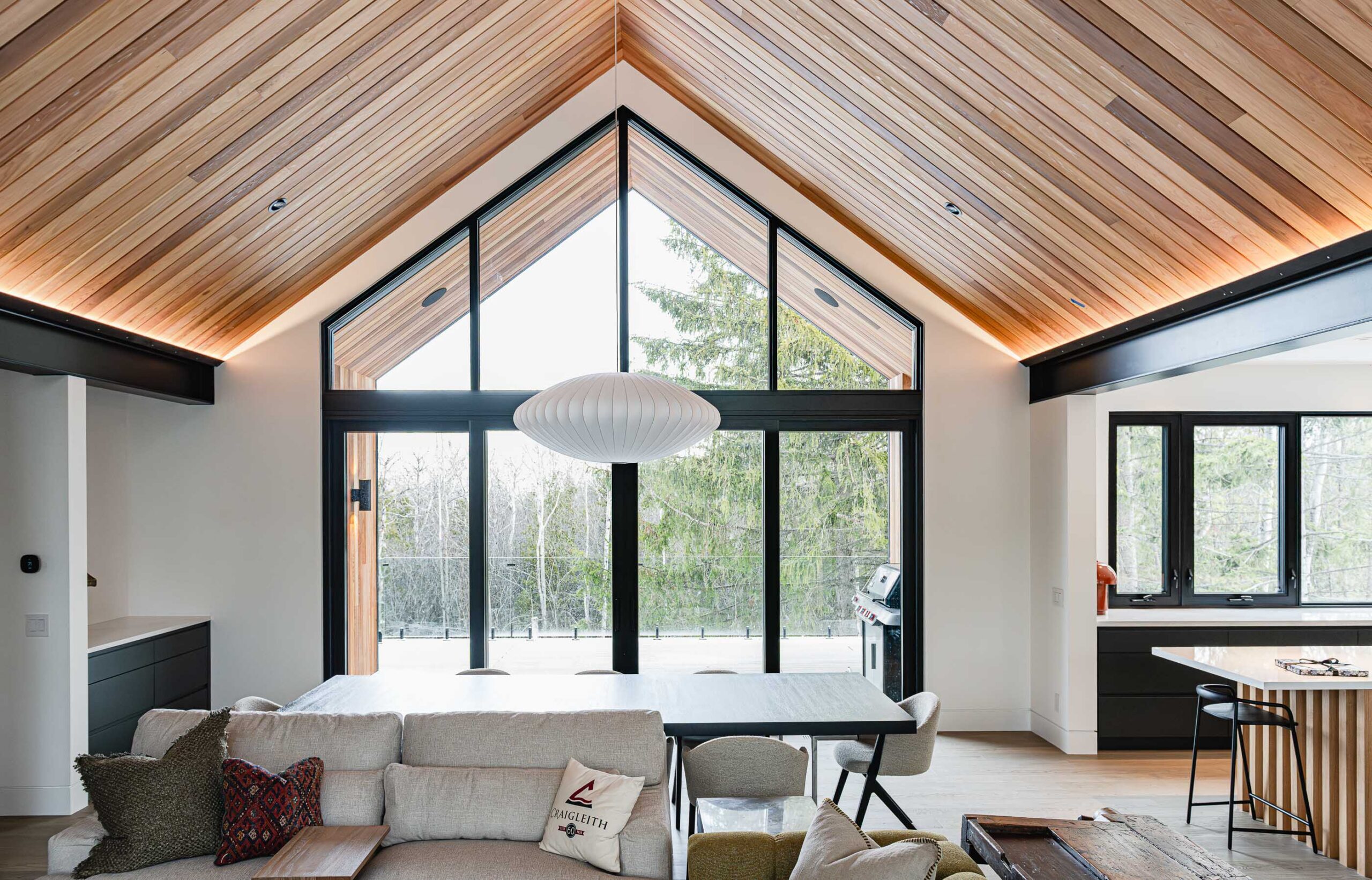 Modern alpine-inspired ski chalet with vaulted wood ceiling, black framed floor-to-ceiling windows, and contemporary lines.