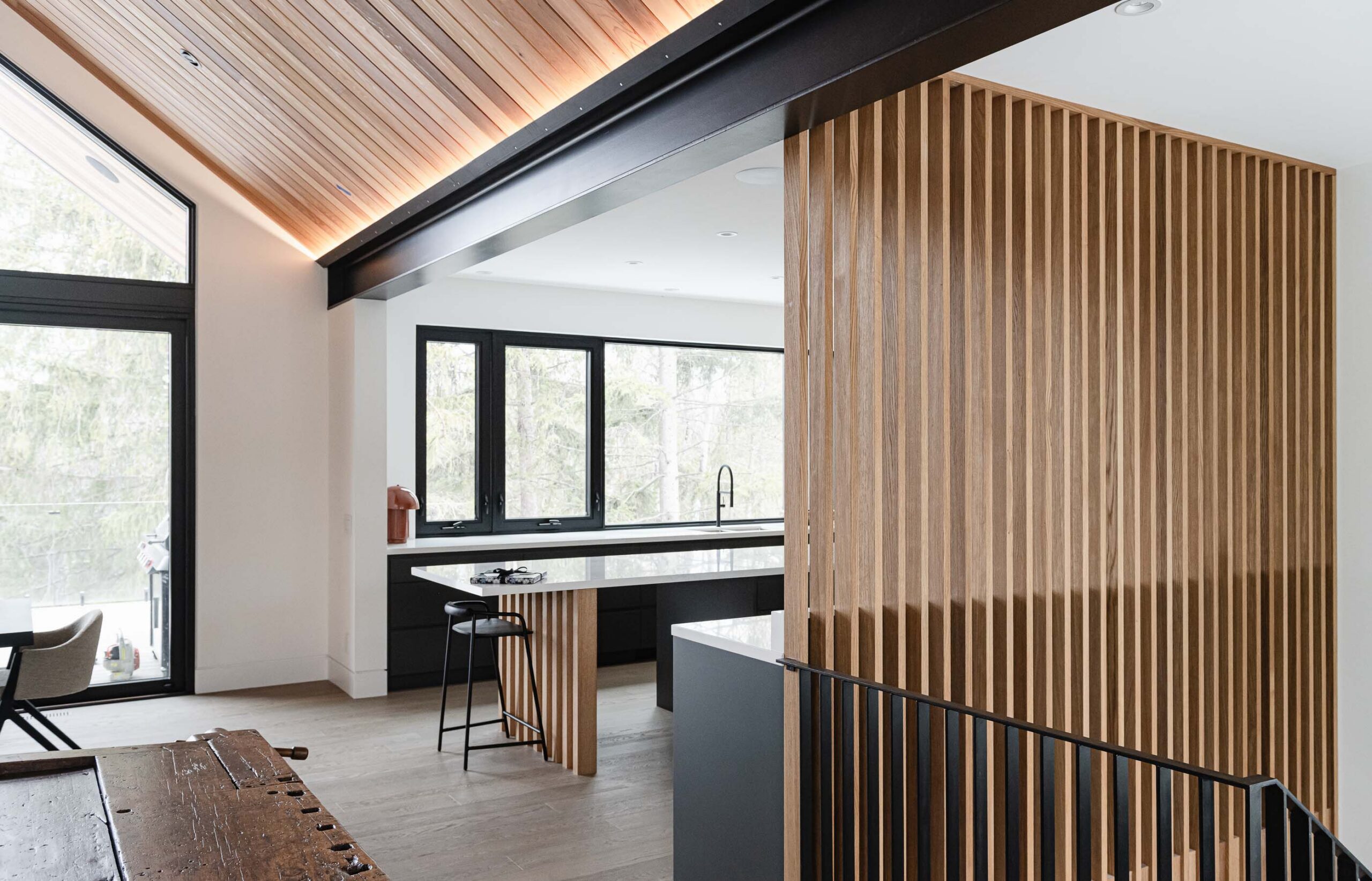 Contemporary Blue Mountain chalet kitchen with slotted wood wall divider, industrial metal accents, and extensive forest views