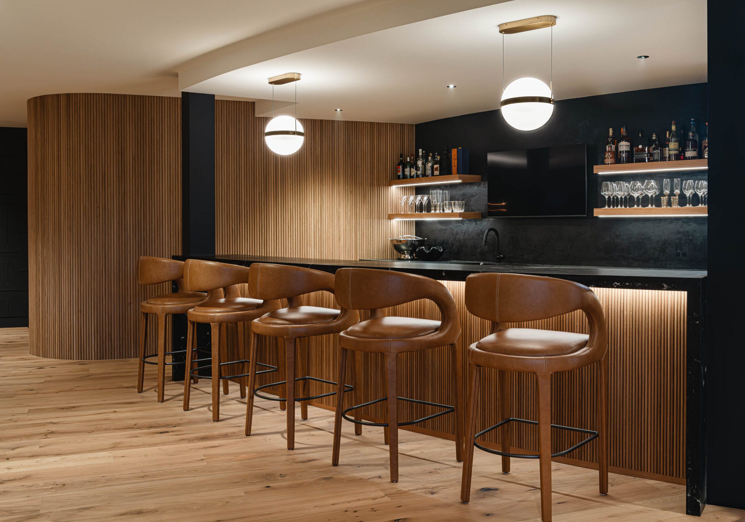 Curved bar with contemporary finishes, dark marble counters and fluted wood details