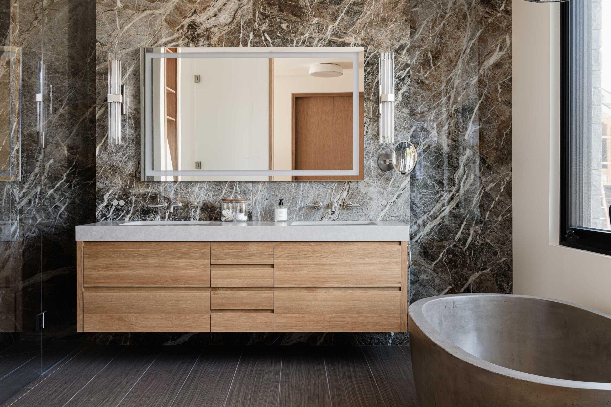 Contemporary Blue Mountain chalet bathroom with marble walls, poured concrete bathtub, and modern finishes