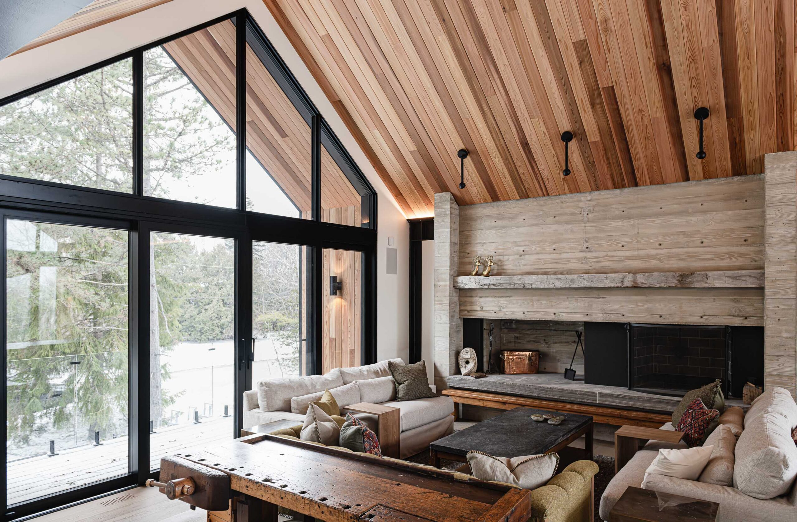 Modern Blue Mountain chalet with vaulted ceiling, oversized patio doors, and board-formed concrete fireplace with reclaimed timber mantle