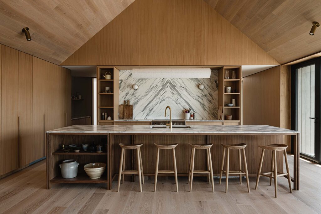 Modern barn kitchen with bookmatched quartz backsplash, custom walnut cabinetry and island, and contemporary brass fixtures
