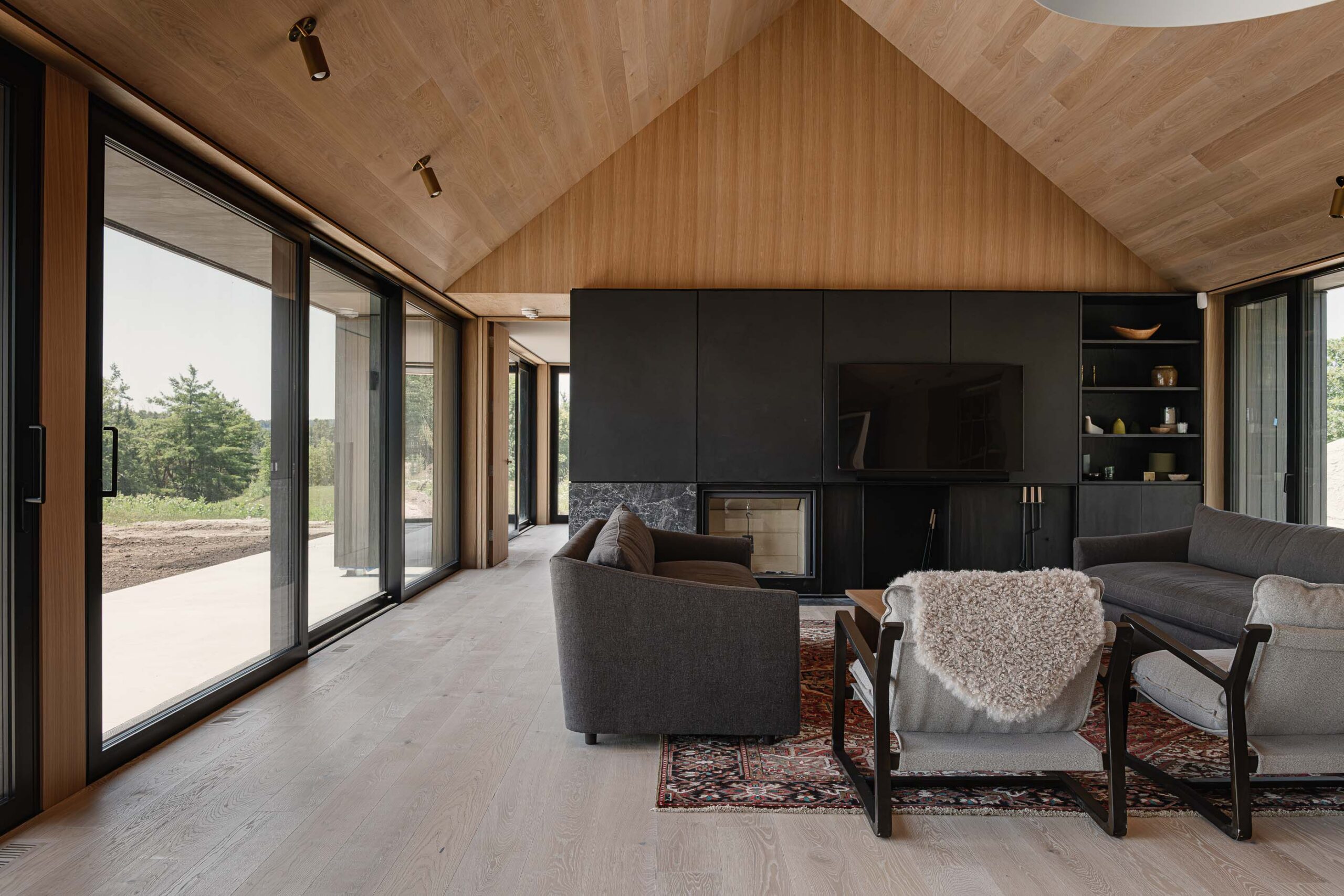 Living room detail of a Scandi-style modern barn home with modern fireplace and extensive glazing and views of the surrounding landscape