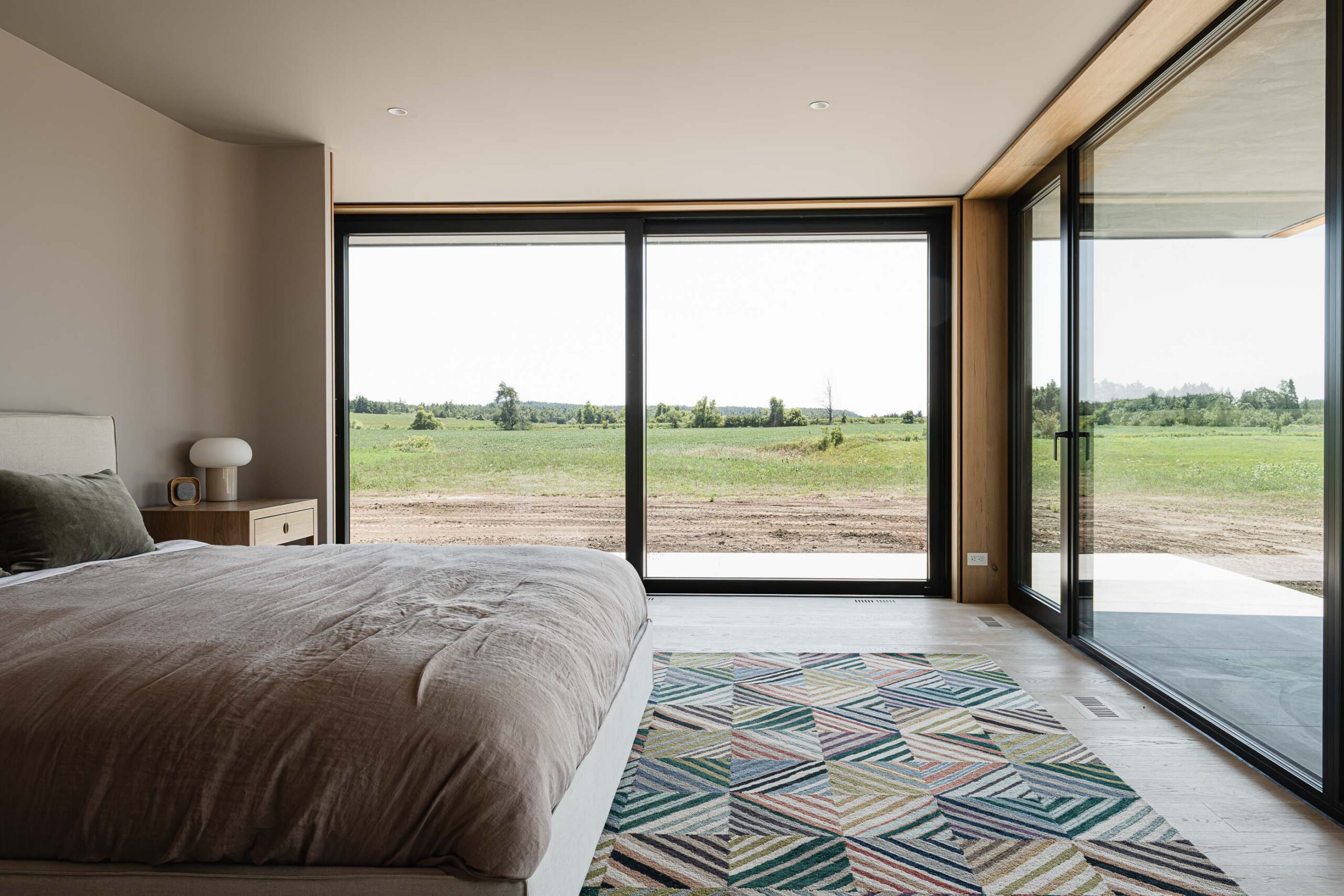 primary bedroom in a modern barn home being built, with oversized sliding doors and views of the surrounding farmland
