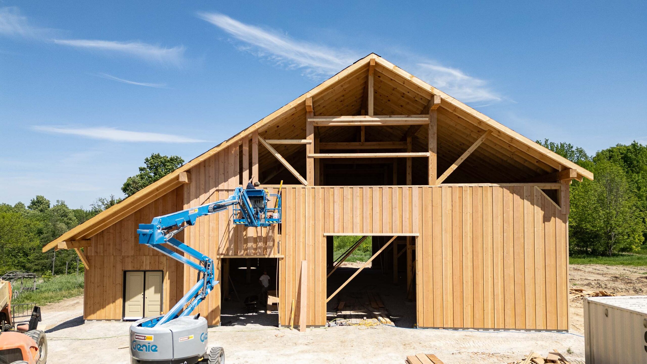 front elevation of a modern timber frame barn as exterior siding is being completed