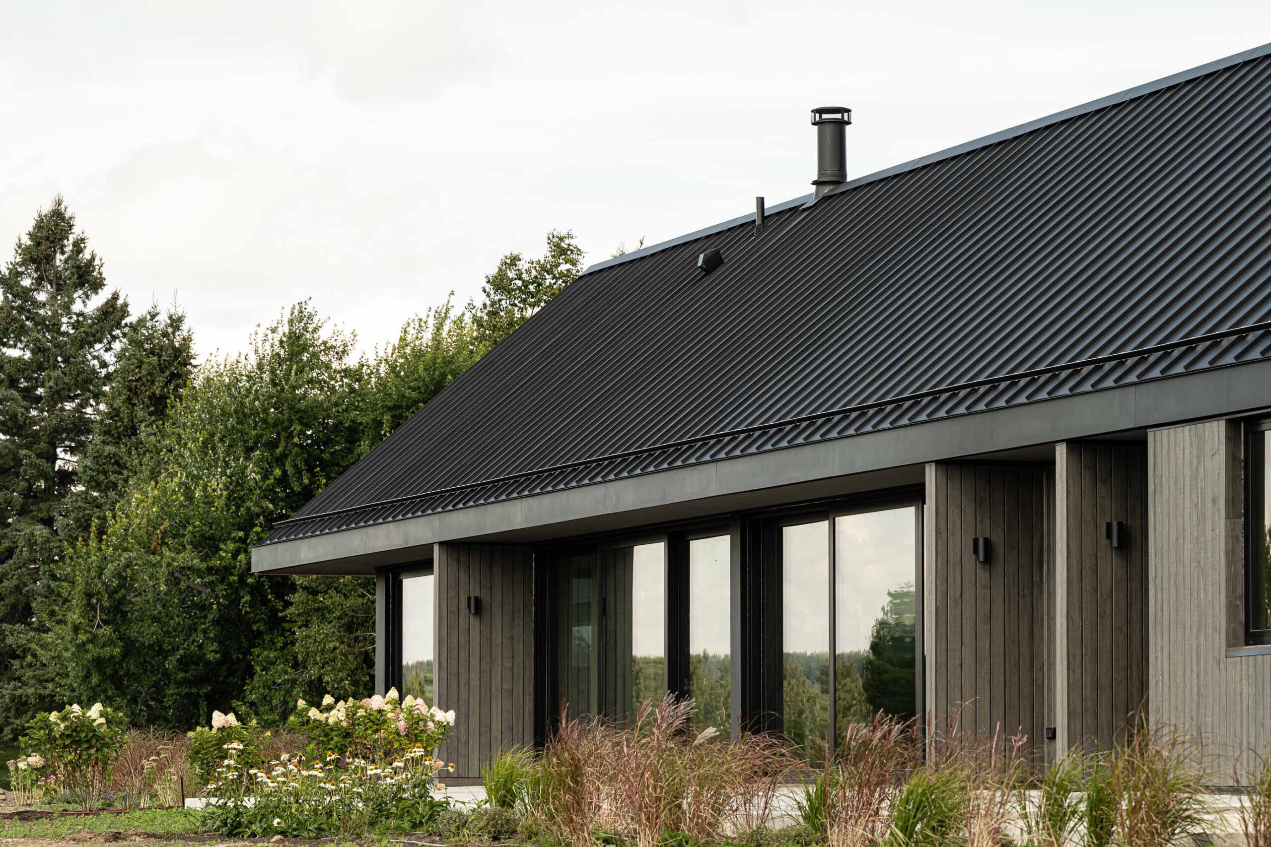 side elevation of a modern barn being built by a Collingwood custom home builder, with landscaping in progress