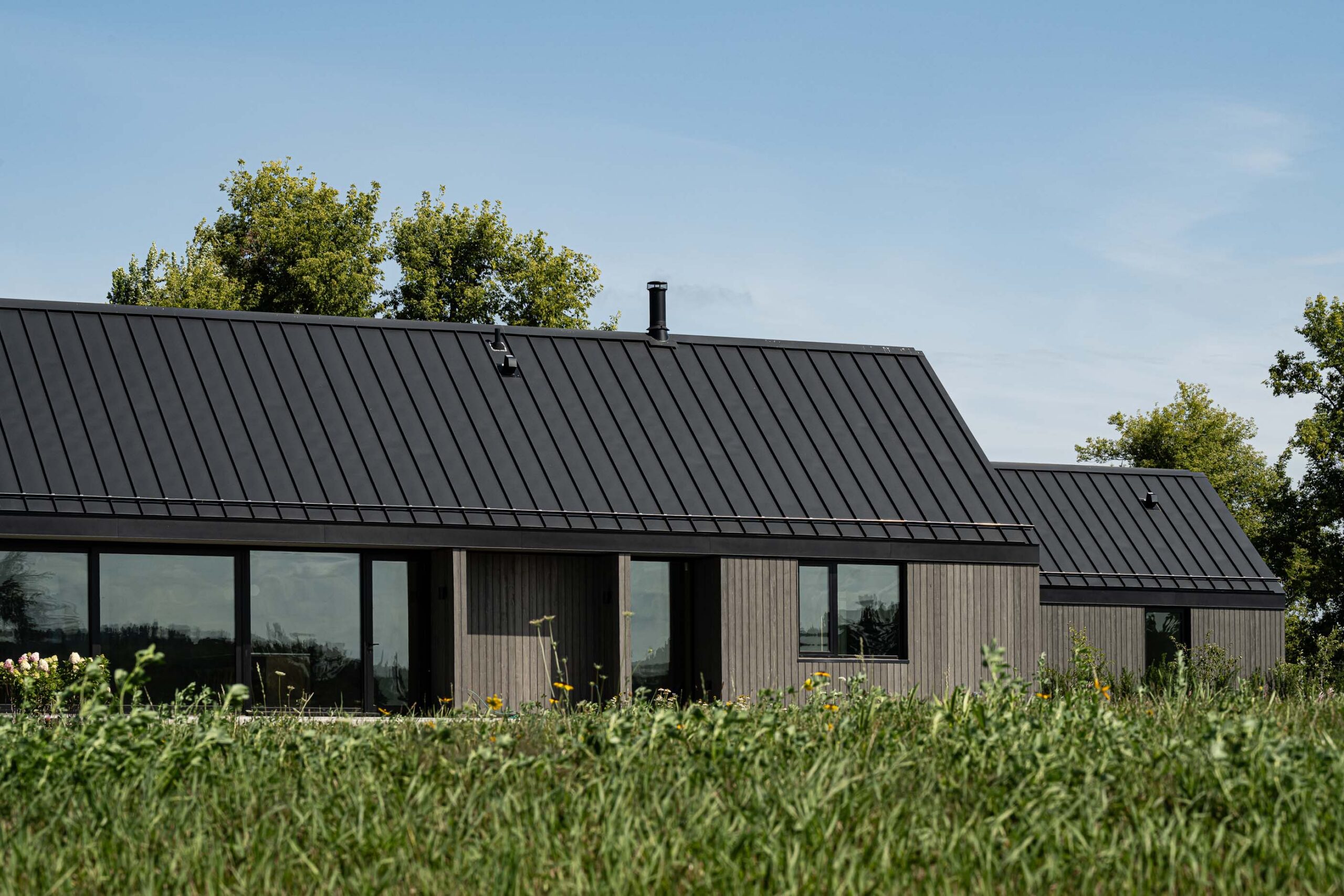 side elevation of a Scandinavian-style modern barn build with extensive glazing, oversized sliding door, and farmland views