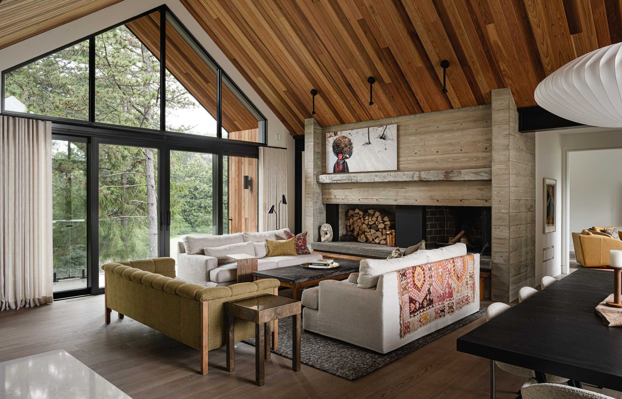 Modern Blue Mountain chalet with vaulted ceiling, oversized patio doors, and board-formed concrete fireplace with reclaimed timber mantle