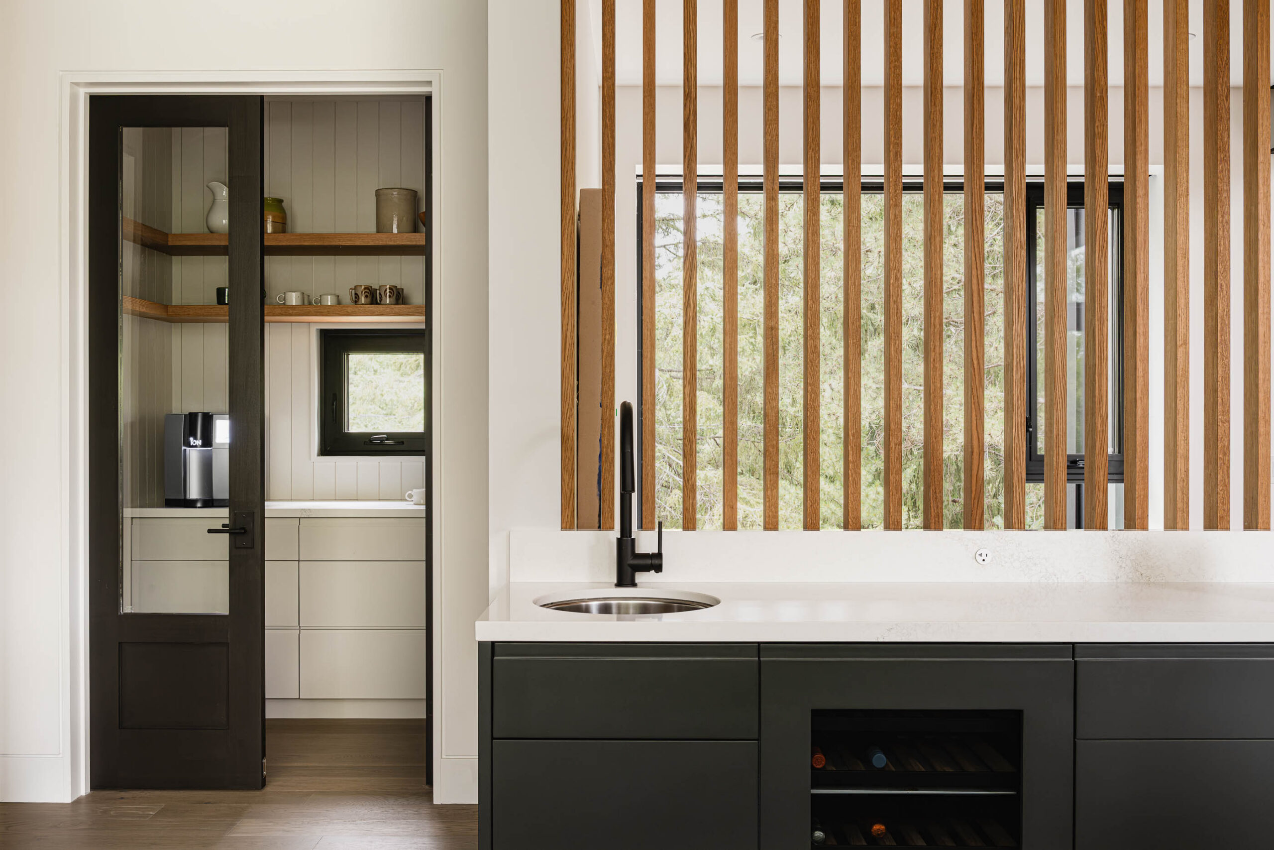 Slat wood wall detail in a contemporary kitchen with custom cabinetry, quartz counters and pantry featuring a coffee station