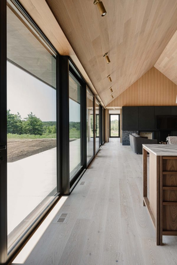 view along the floor-to-ceiling glazed wall spanning the kitchen, dining and living rooms of a modern barn build