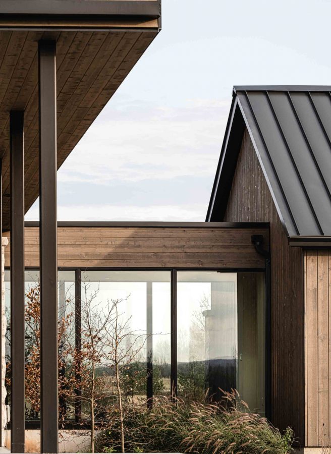 Architectural detail of a contemporary country home featuring the modern lines of a glass breezeway, warm wood siding and metal accents