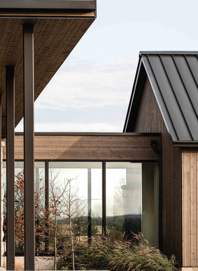 10-contemporary-farmhouse-website Architectural detail of a contemporary country home featuring the modern lines of a glass breezeway, warm wood siding and metal accents