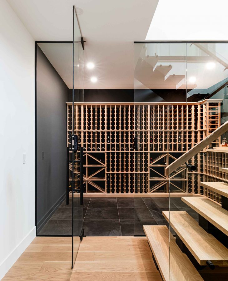 a modern cellar with floor to ceiling glass wall in a custom home