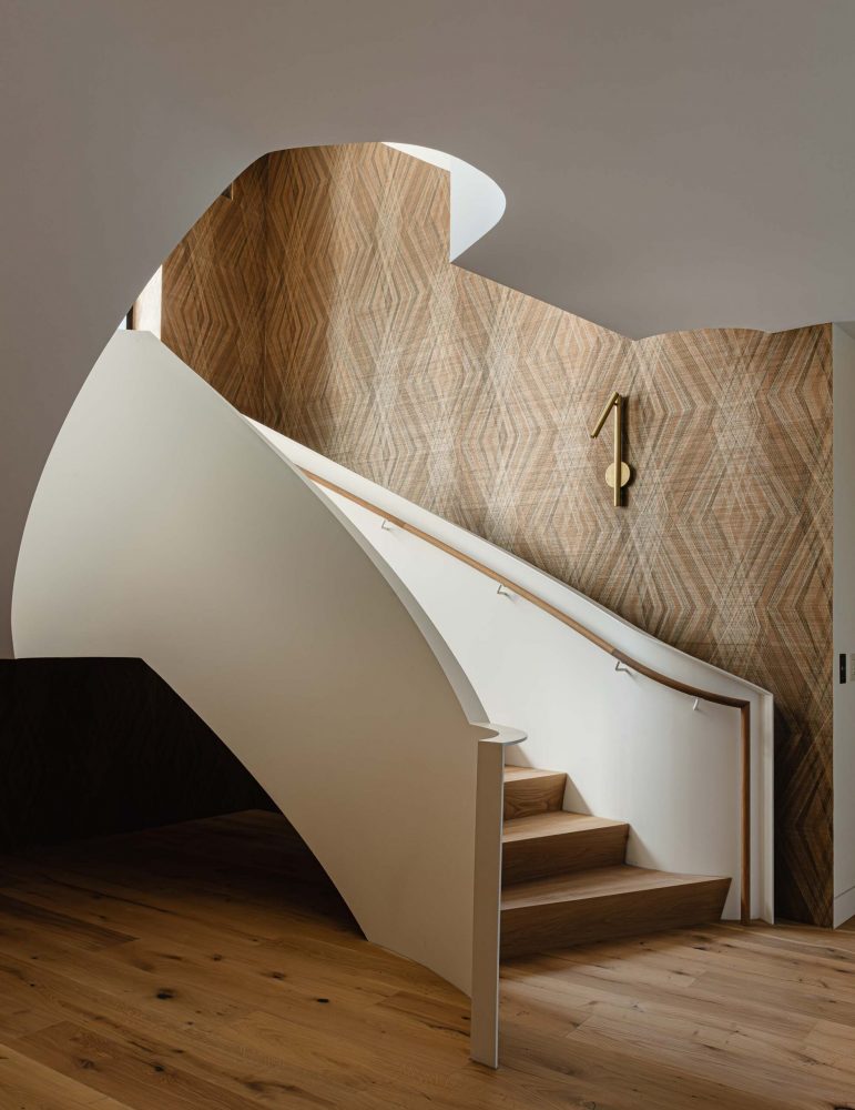 Architectural detail of a freestanding curved metal staircase with oak treads and handrail in a Blue Mountain home