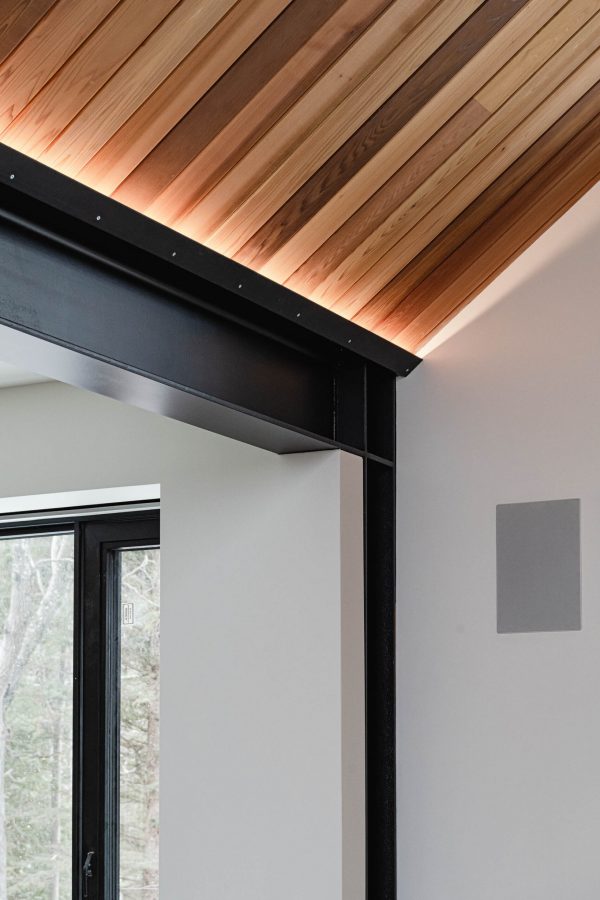 Integrated up-lighting detail in a modern ski chalet with vaulted wood ceiling, industrial metal beam accents
