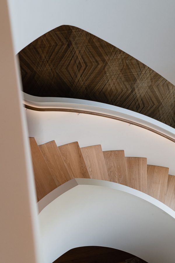 Architectural detail of a freestanding curved metal staircase with oak treads and handrail in a modern Blue Mountain home