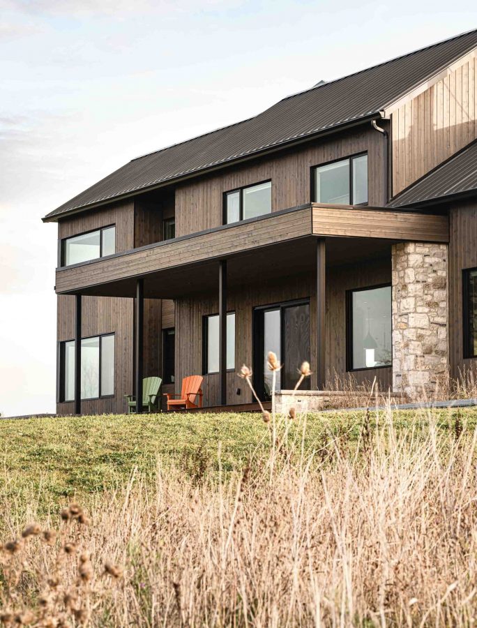 Front exterior of a modern farmhouse designed with stone, wood, metal and sleek lines