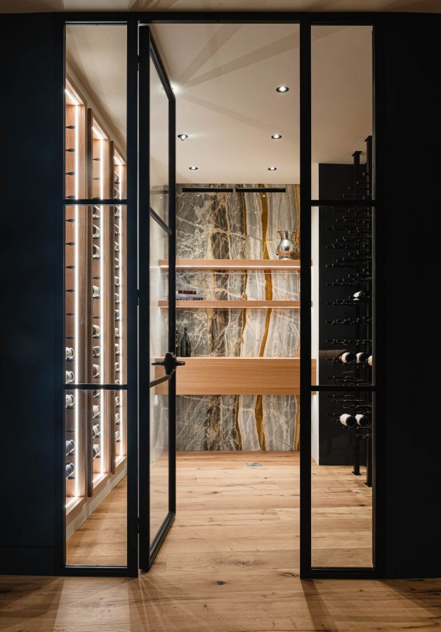 Contemporary wine cellar with glass walls, metal detailing and marble accent wall