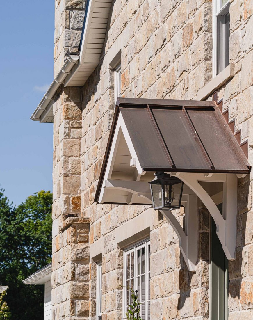 Stone masonry and copper roof detail on an English-style stone house built by a Collingwood custom home builder