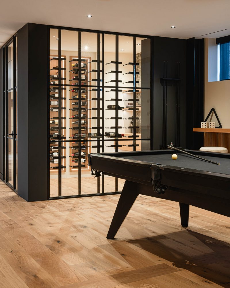 Contemporary wine cellar with glass walls and specialty lighting in a modern Blu Mountain chalet