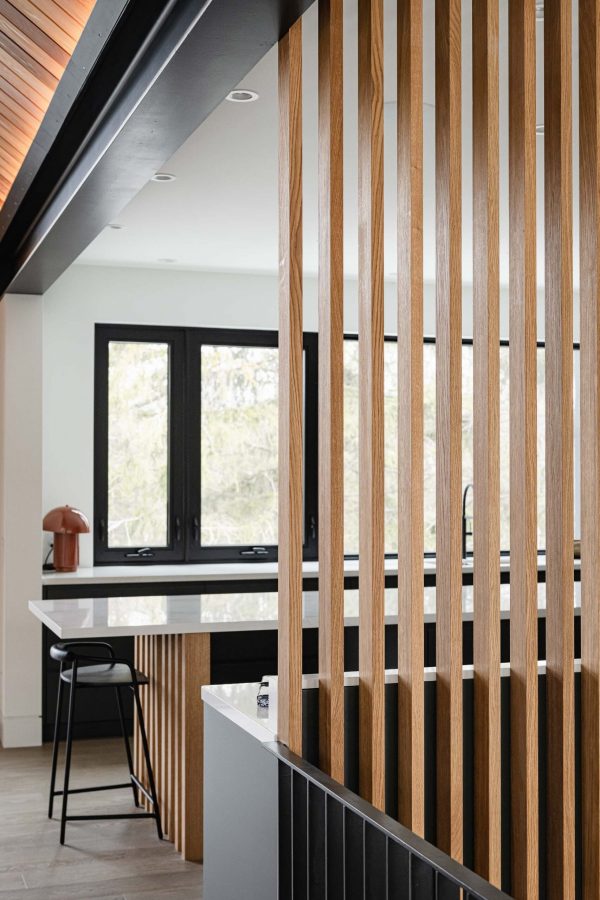 slotted wood wall detail in a modern ski chalet looking into the contemporary kitchen