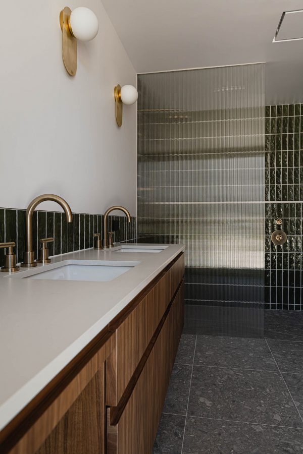 bathroom detail of a contemporary ensuite being built, featuring brass fixtures, fluted glass shower wall and custom vanity